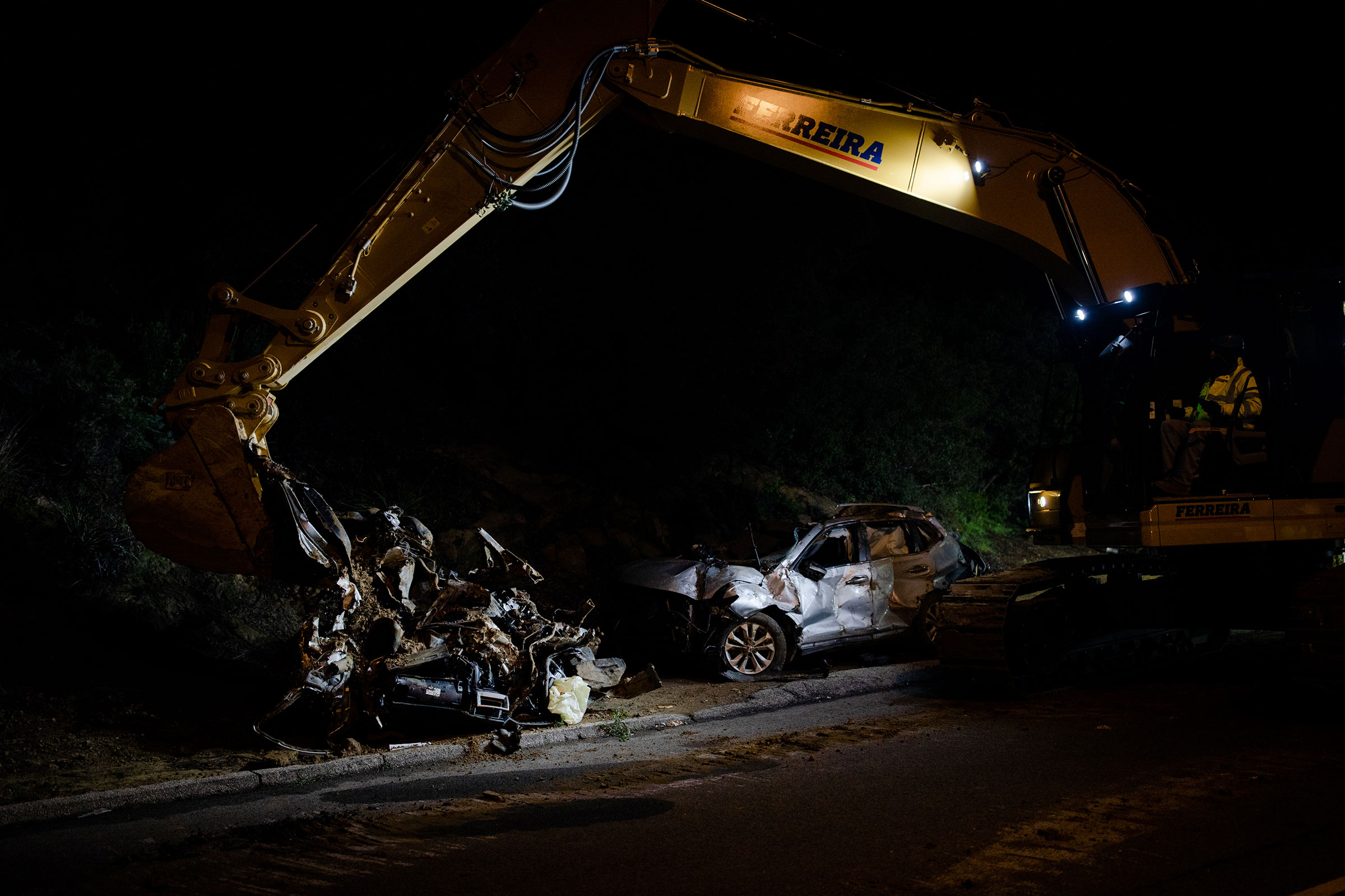 LOS ANGELES, CALIFORNIA - January 10th, 2023: Workers pull what remains of a car from a sinkhole that opened up in the Chatsworth neighborhood of Los Angeles.CREDIT: Alex Welsh for TIME