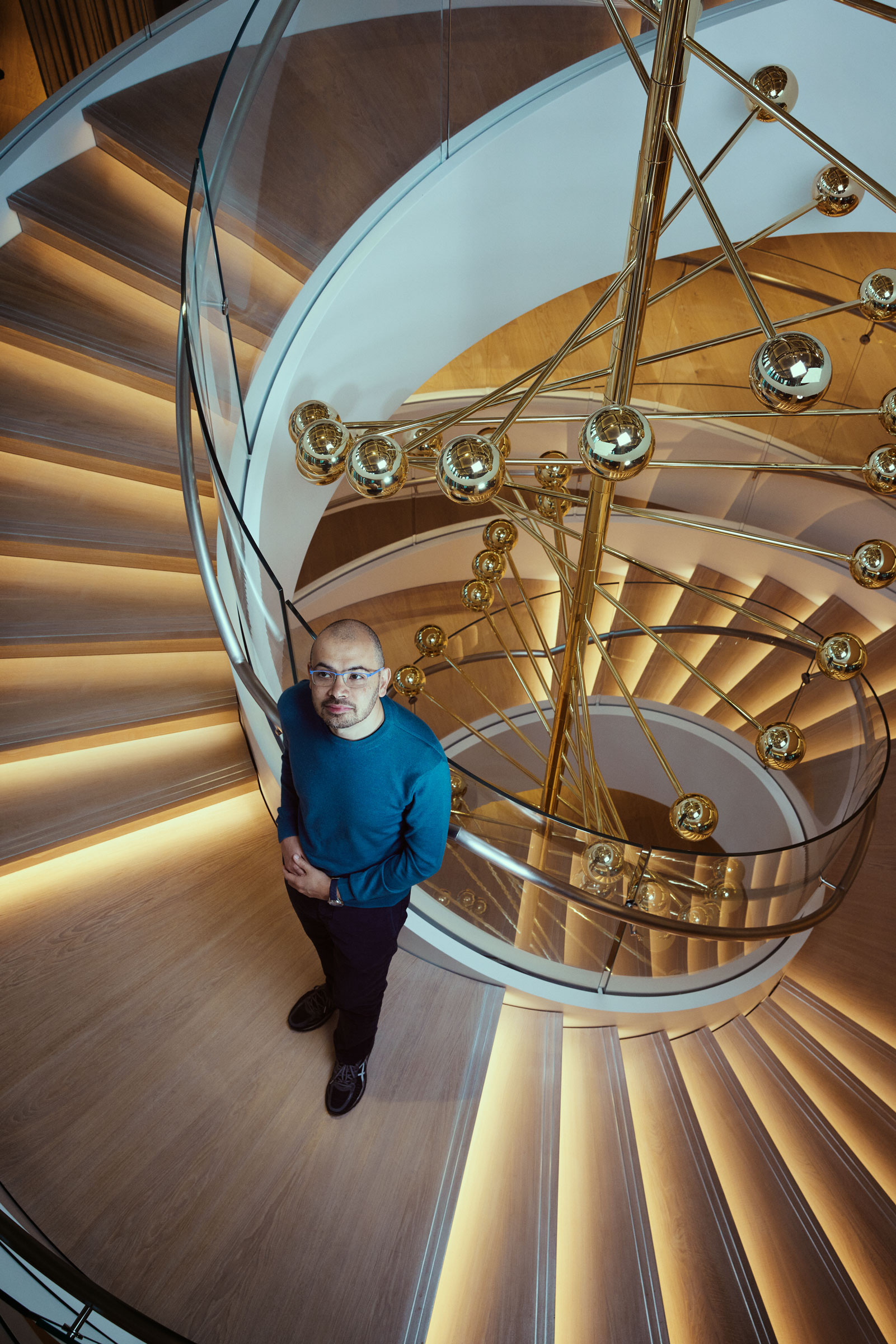 Demis Hassabis by the <em>Helicase</em>—a sculpture that uses DNA’s helix shape as a symbol of human endeavor and the pursuit of knowledge—at DeepMind’s headquarters in London on Nov. 3, 2022 (James Day for TIME)