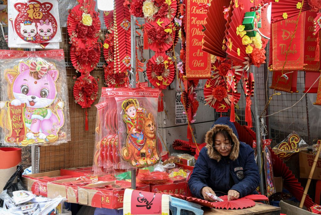 A shopkeeper at a stall that is selling cat images ahead of the Lunar New Year at a market in the old quarters of Hanoi, Jan. 17, 2023. As China gears up to welcome the Year of the Rabbit, celebrations are slightly different in Vietnam, where the Year of the Cat is about to begin. (Nhac Nguyen—AFP via Getty Images)