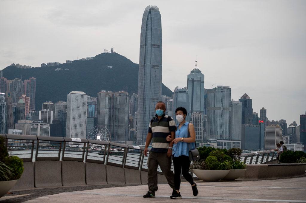 People wearing face masks walks in front of the Hong Kong Skyline on October 17, 2022 in Hong Kong, China. (Vernon Yuen–NurPhoto/Getty Images)