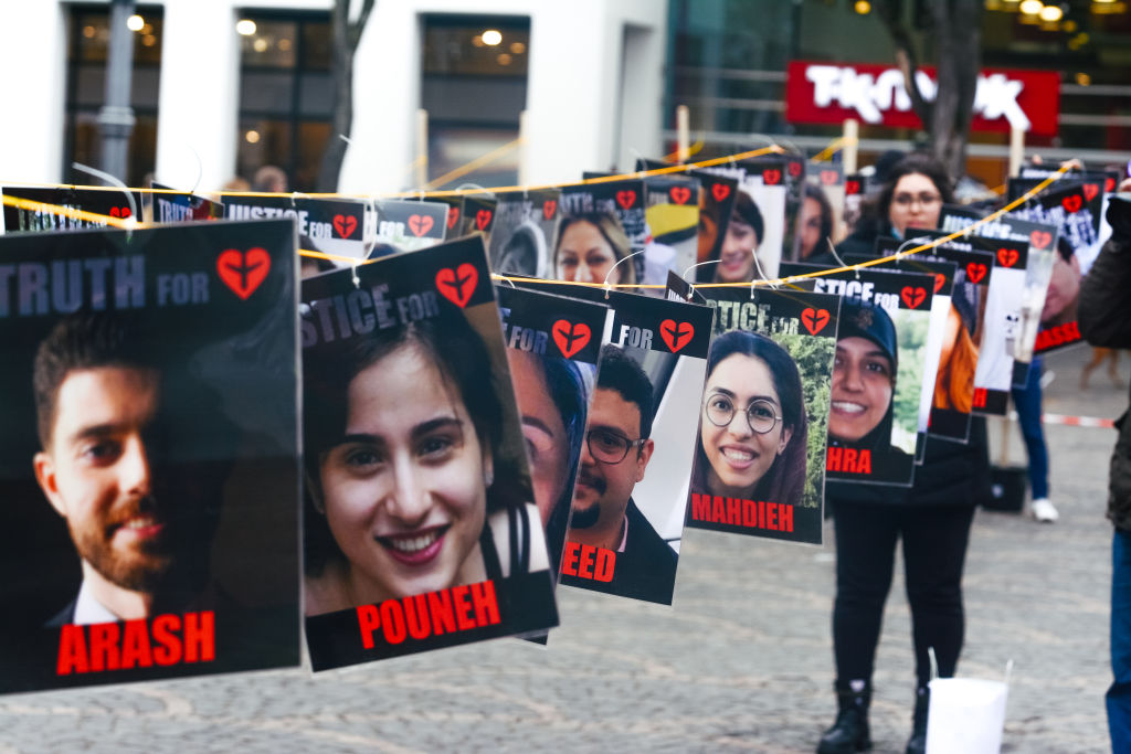 Photos of passengers aboard PS752, which was downed by the Iranian regime, are seen during a protest in Bonn, Germany on January 7, 2023. ((Ying Tang/NurPhoto — Getty Images))