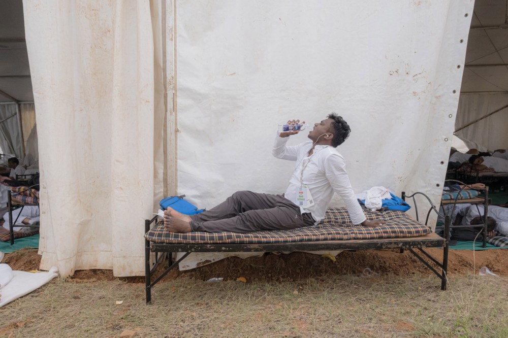 A participant in the Bharat Jodo Yatra, or the Unite India March, rests on cot as fellow travelers rest inside a tent
