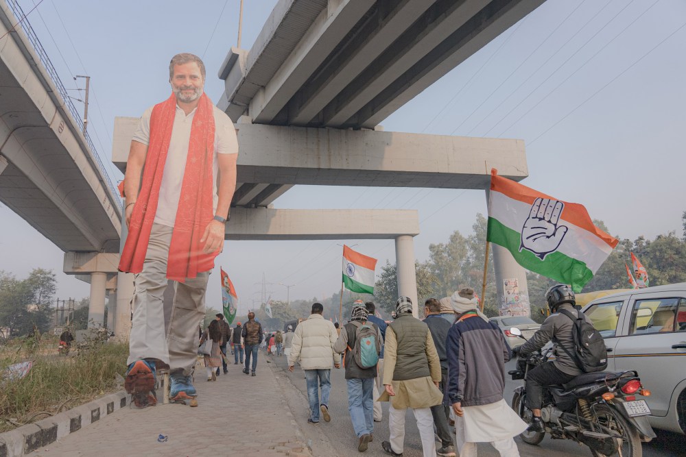 Supporters of Indian National Congress walk by a cut-out of Rahul Gandhi