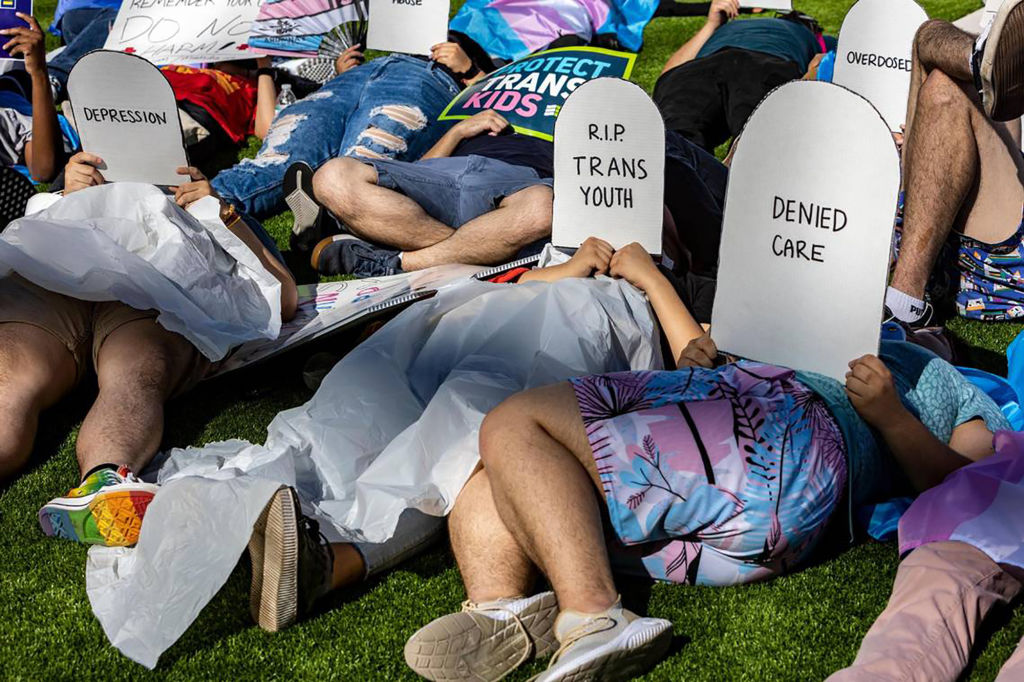 Protesters lie on the ground in front of the Marriott Fort Lauderdale Airport, where the Florida Board of Medicine was meeting to discuss banning gender-affirming medical treatment for youths, on Aug 5, 2022. (Jose A. Iglesias—El Nuevo Herald/Tribune News Service via Getty Images)