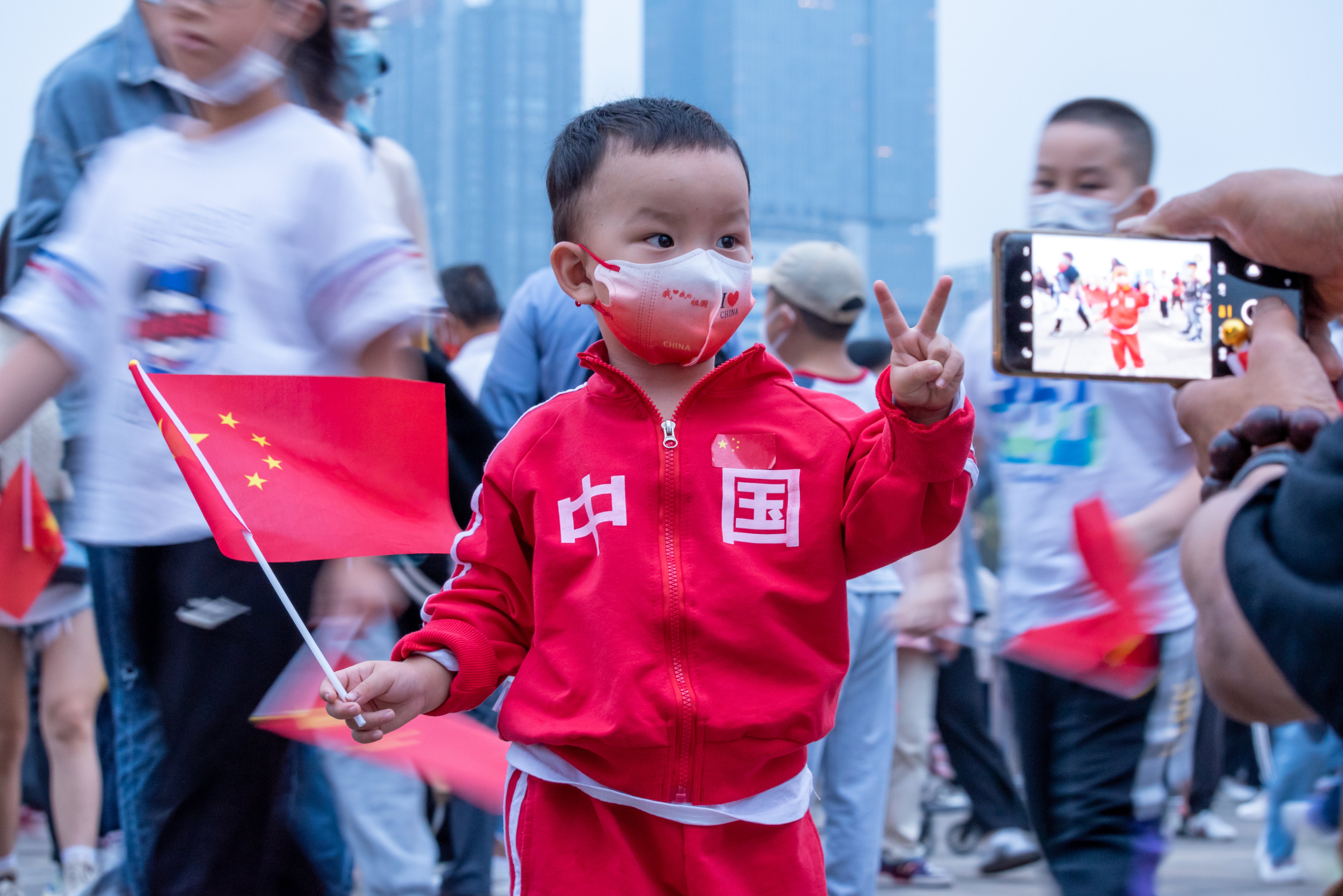 2022 年 10 月 1 日，在四川成都舉行的慶祝中華人民共和國成立 73 週年的升旗儀式上，一名兒童在天府廣場拍照留念。（Wu Ke—VCG/Getty Images )