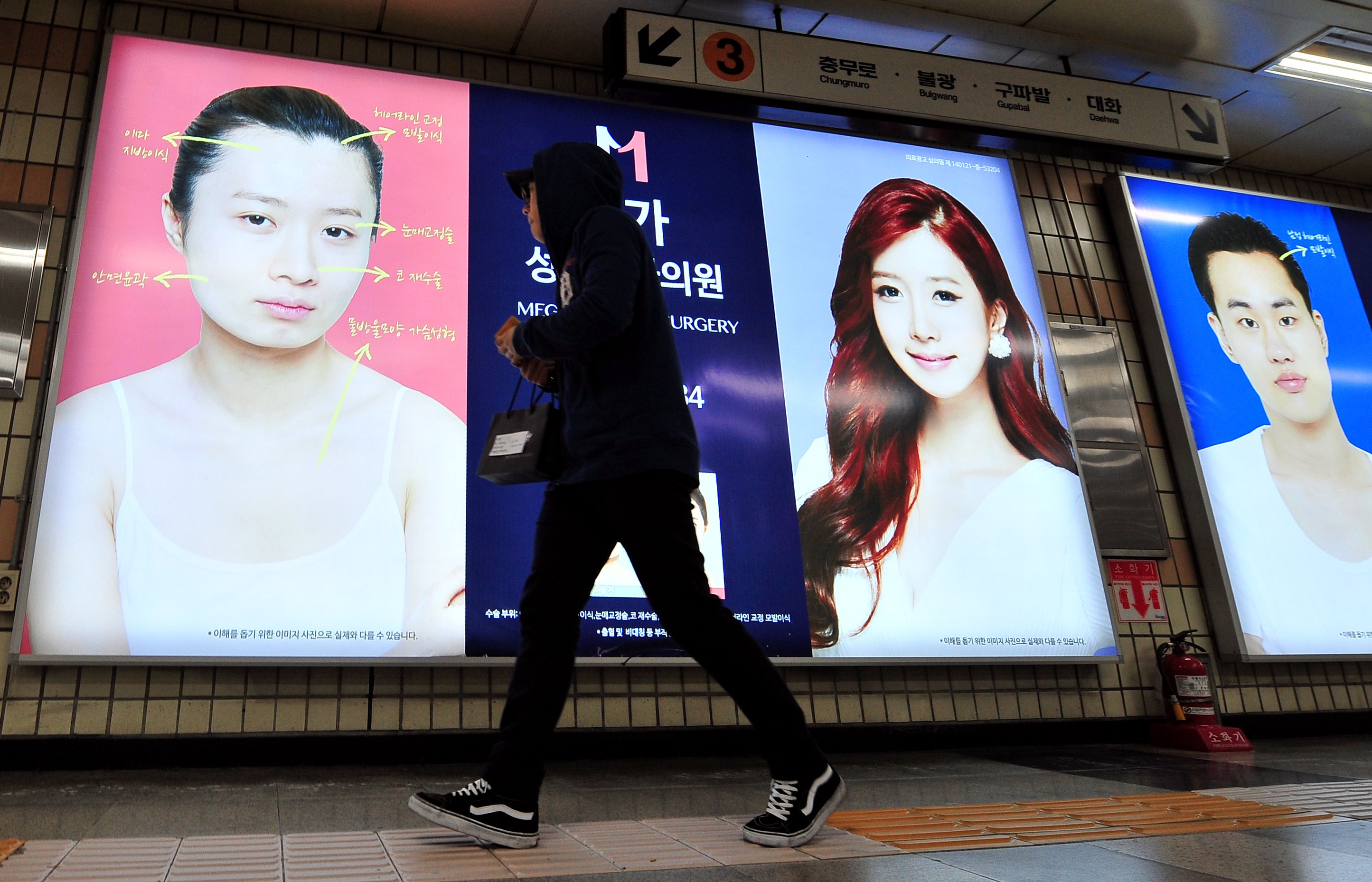 A pedestrian walks past advertisements for plastic surgery clinics at a subway station in Seoul in March 2014. (Jung Yeon-je—AFP/Getty Images)