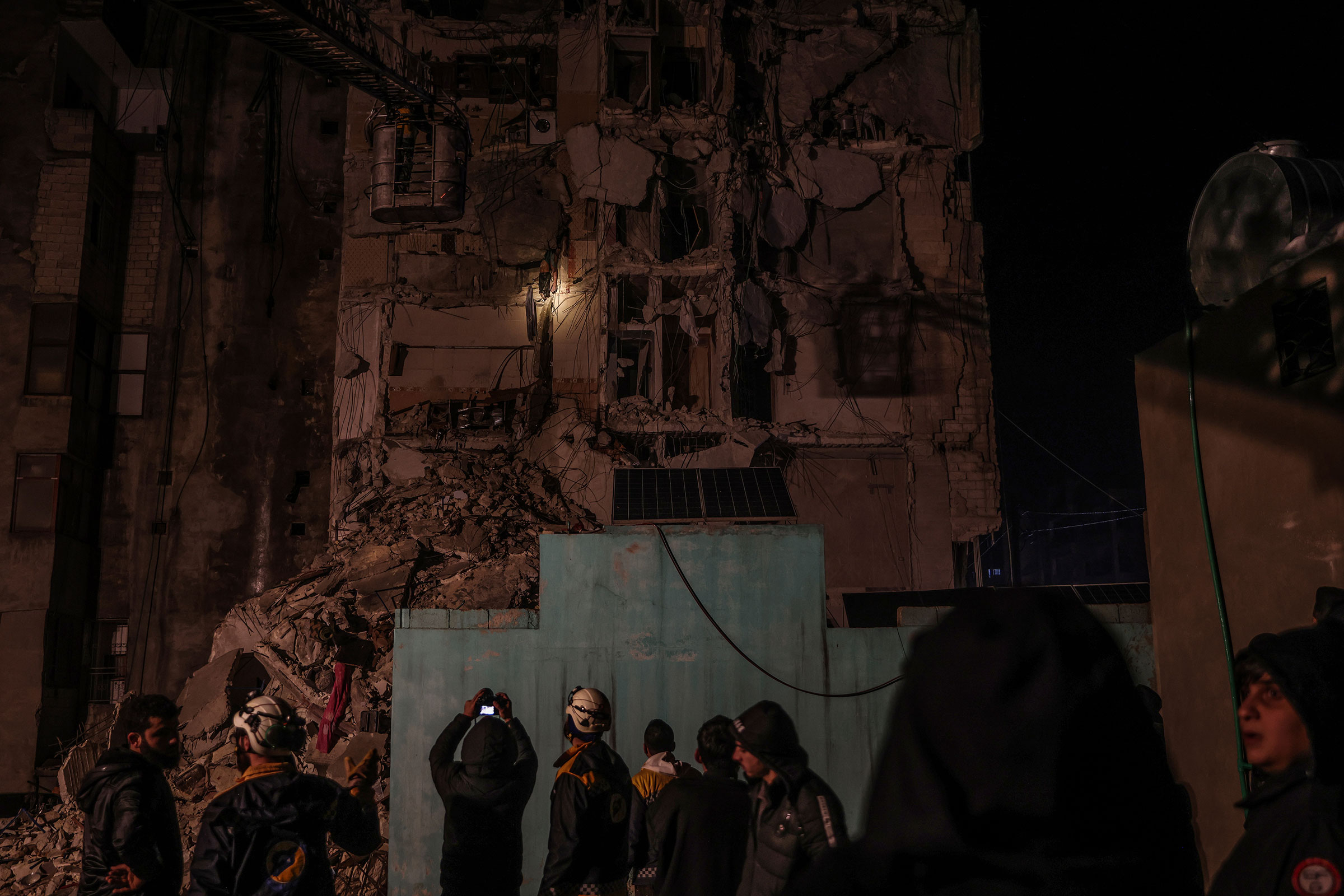 Suriyeli siviller ve Beyaz Miğferler üyeleri, 6 Şubat 2023'te Suriye'yi vuran 7,8 büyüklüğündeki depremin ardından yıkılan bir binanın altında mahsur kalan insanları kurtarmak için çalışıyor. (Anas Alkharboutli—picture-alliance/dpa/AP)