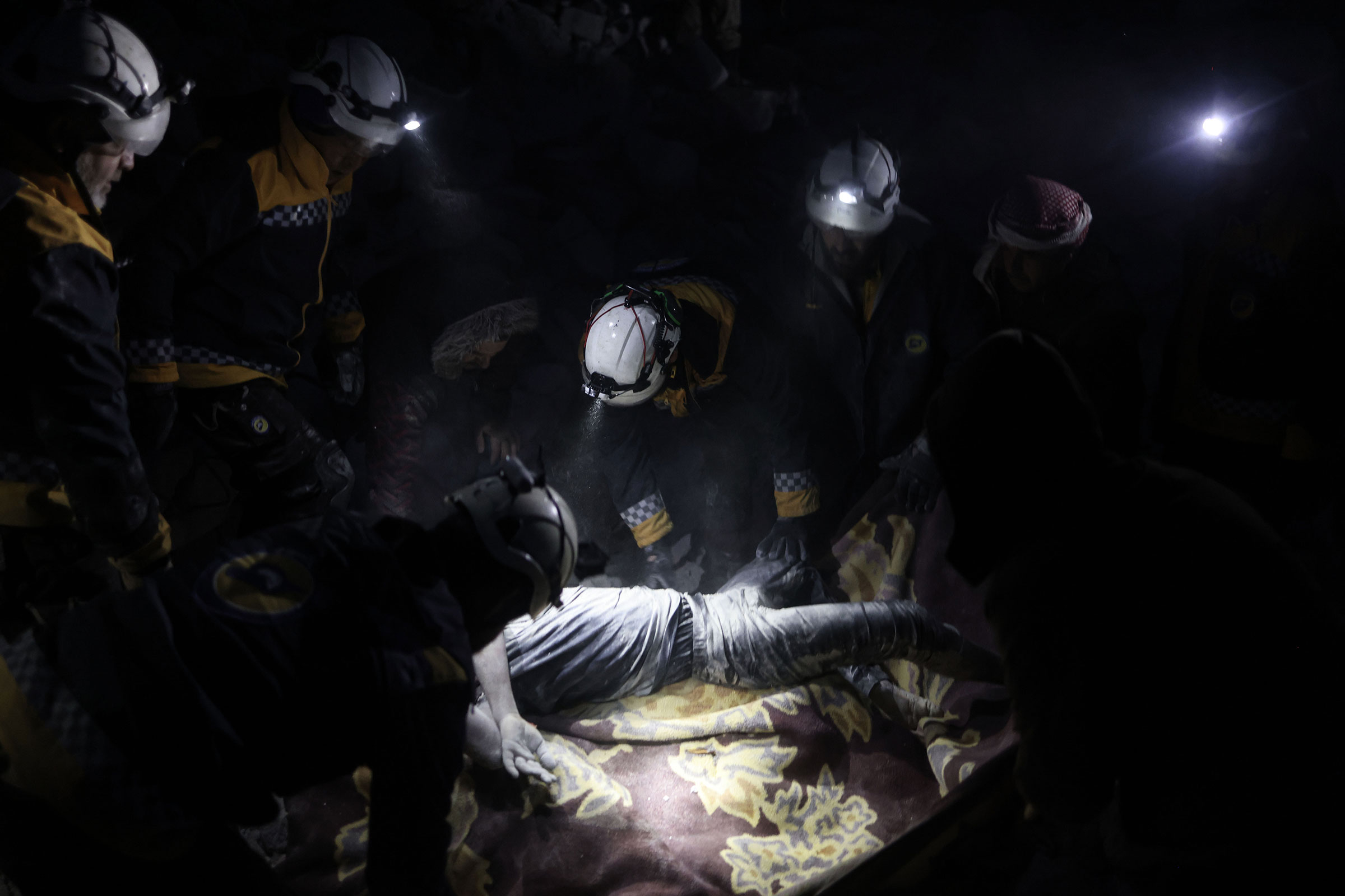 White Helmets members carry the body of a man recovered from under the debris of a collapsed building in the city of Harem following the devastating earthquake that struck the Turkish-Syrian border. (Anas Alkharboutli—picture alliance/Getty Images)