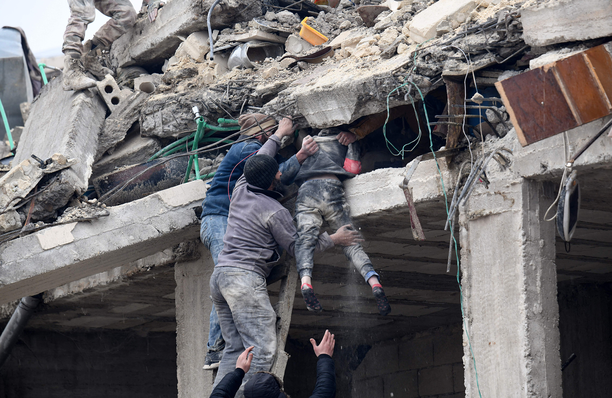 Sakinler, Suriye'nin kuzeybatısındaki Afrin i şehrinin kırsalındaki Jandaris kasabasında meydana gelen depremin ardından çöken bir binanın enkazından yaralı bir kızı çıkarıyor (Rami Al Sayed—AFP/Getty Images)