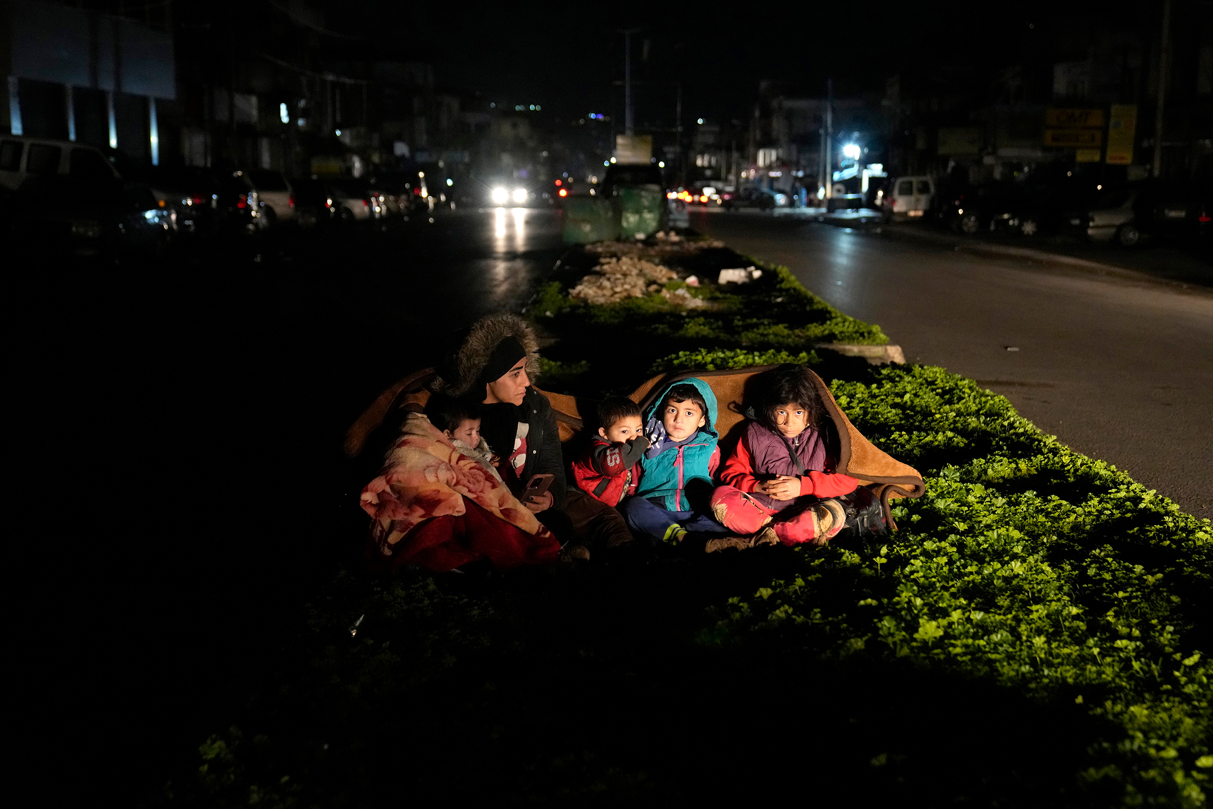 A family sits outside their home in Beirut following an earthquake that hit neighboring Turkey. (Hussein Malla—AP)