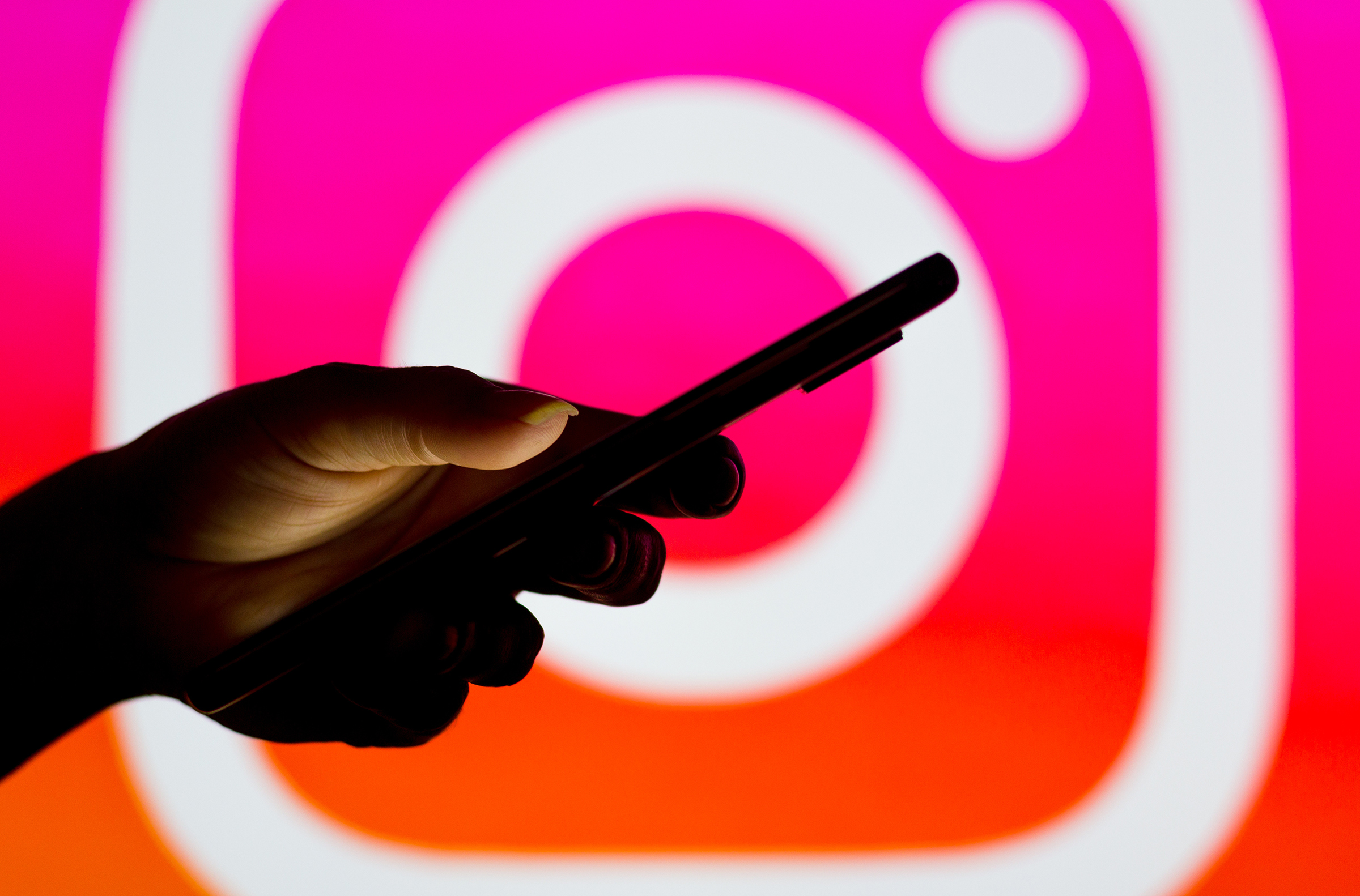 The Instagram logo seen in the background of a silhouette of a woman holding a mobile phone. (Rafael Henrique—SOPA Images/LightRocket/Getty Images)