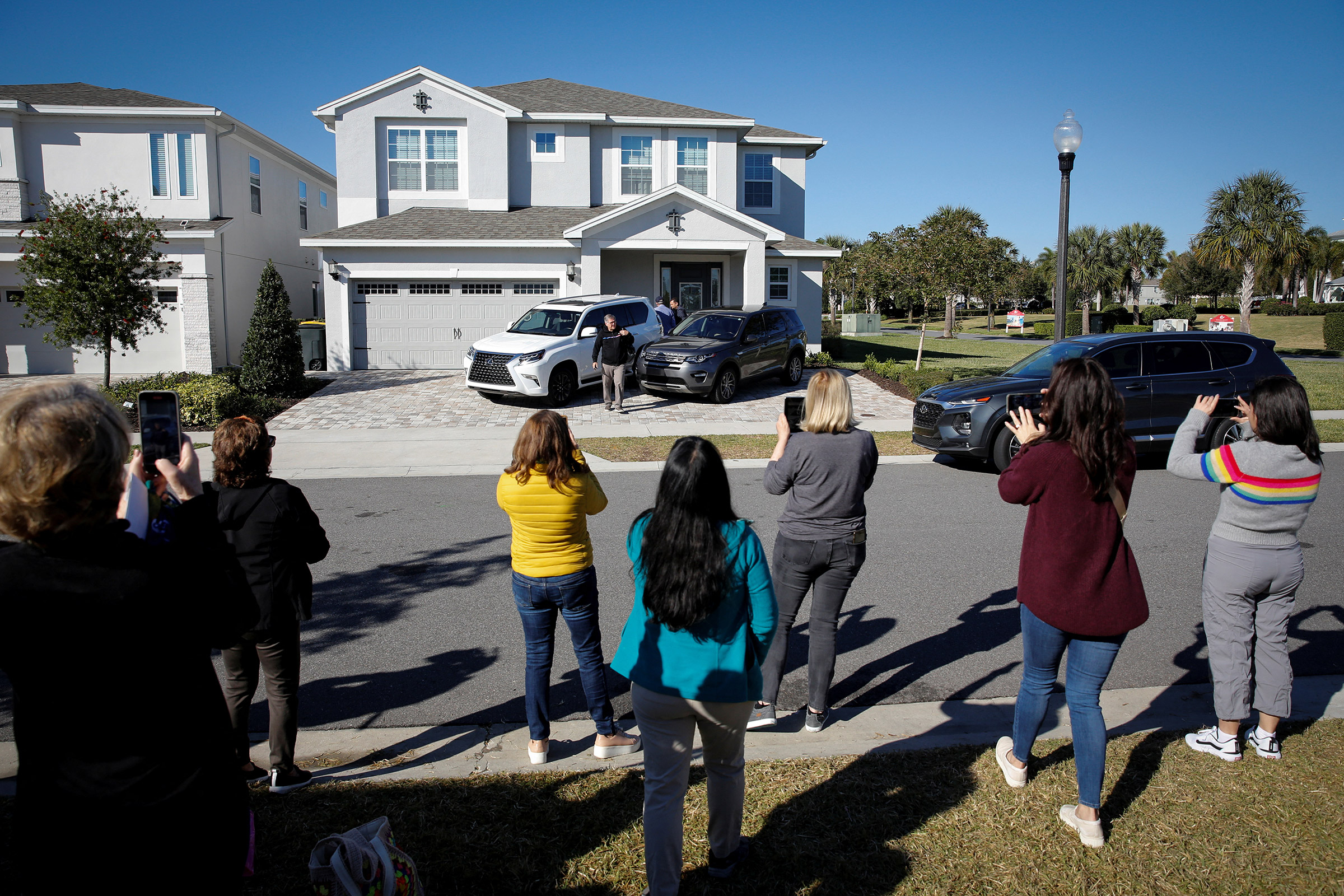 Supporters of former Brazilian President Jair Bolsonaro stand in front of the house he is staying as cardiologist Ricardo Pexoito Camarinha leaves, in Kissimmee, Fla., on Jan. 11, 2023.