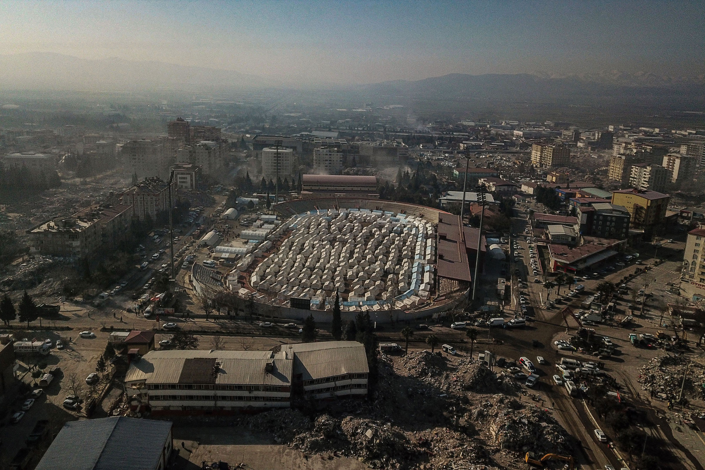 This aerial view shows temporary shelters set up within a stadium amidst collapsed buildings in Kahramanmaras, southeastern Turkey, on Feb. 14, 2023. (Bulent Kilic—AFP/Getty Images)