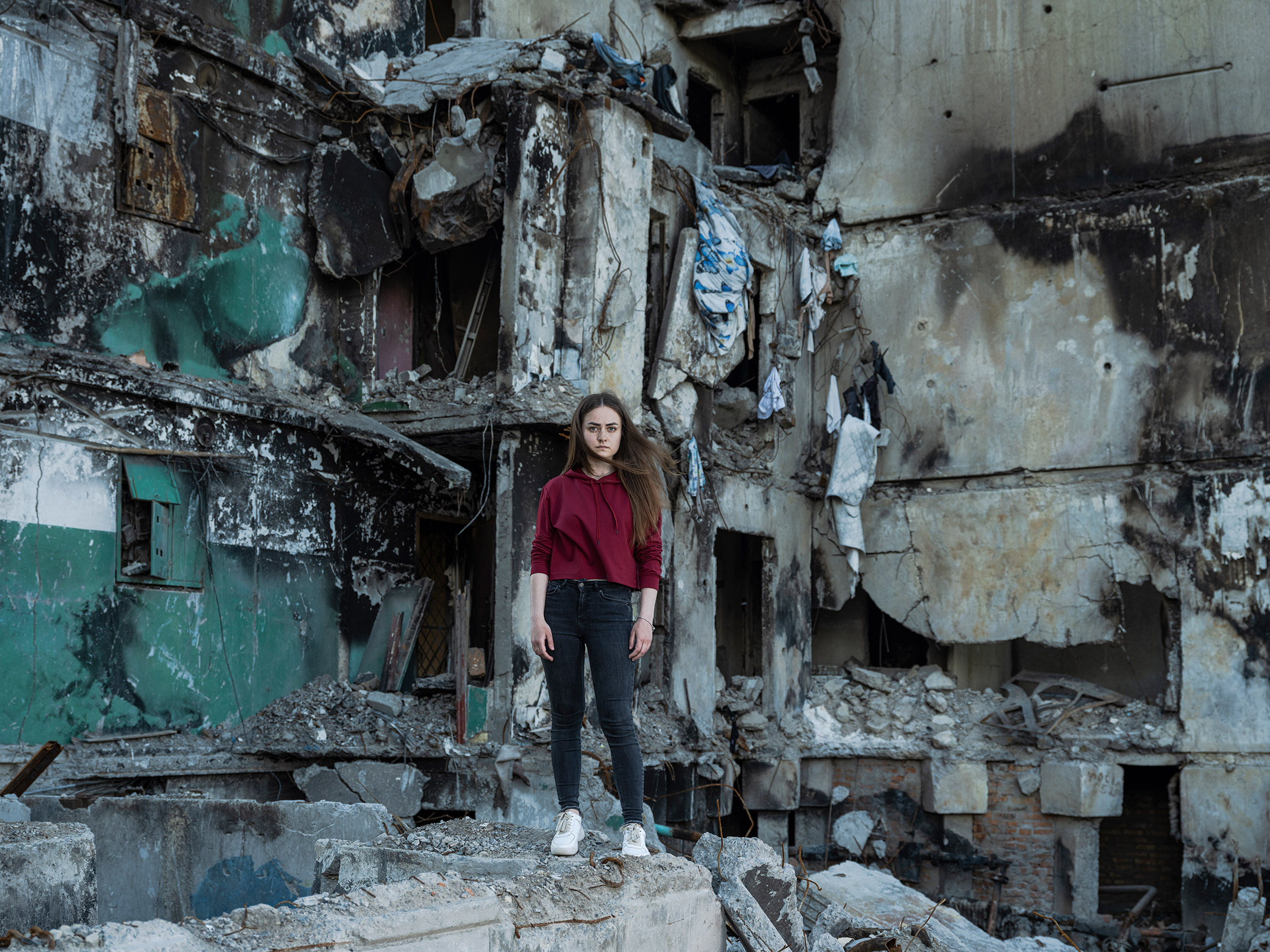 Katya Baranivska, 22, standing in front of the destroyed building in Borodyanka, Ukraine, where her family's apartment used to be before it was destroyed by a Russian bombing. (Sasha Maslov—INSTITUTE)