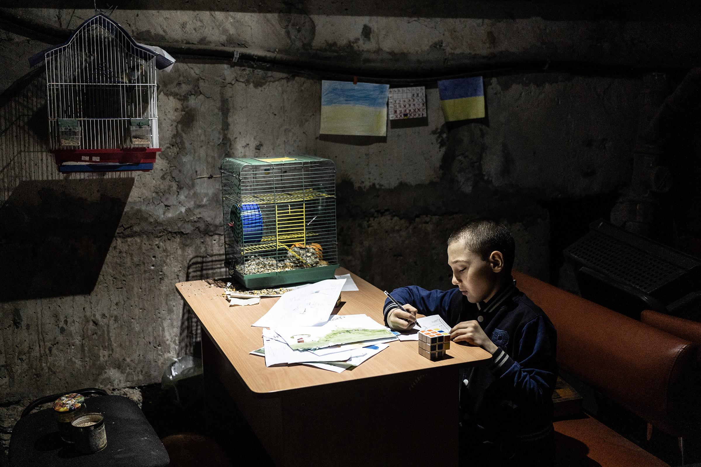 Tymophey, 8, paints in the basement of the kindergarten in Kutuzivka, Ukraine, on May 20, 2022. The village of Kutuzivka was occupied by Russia for weeks and liberated by the Ukrainian army on April 27, 2022. The village was heavily destroyed during fighting, and people are still living in basements in fear of future shelling. (Serhii Korovainyi)