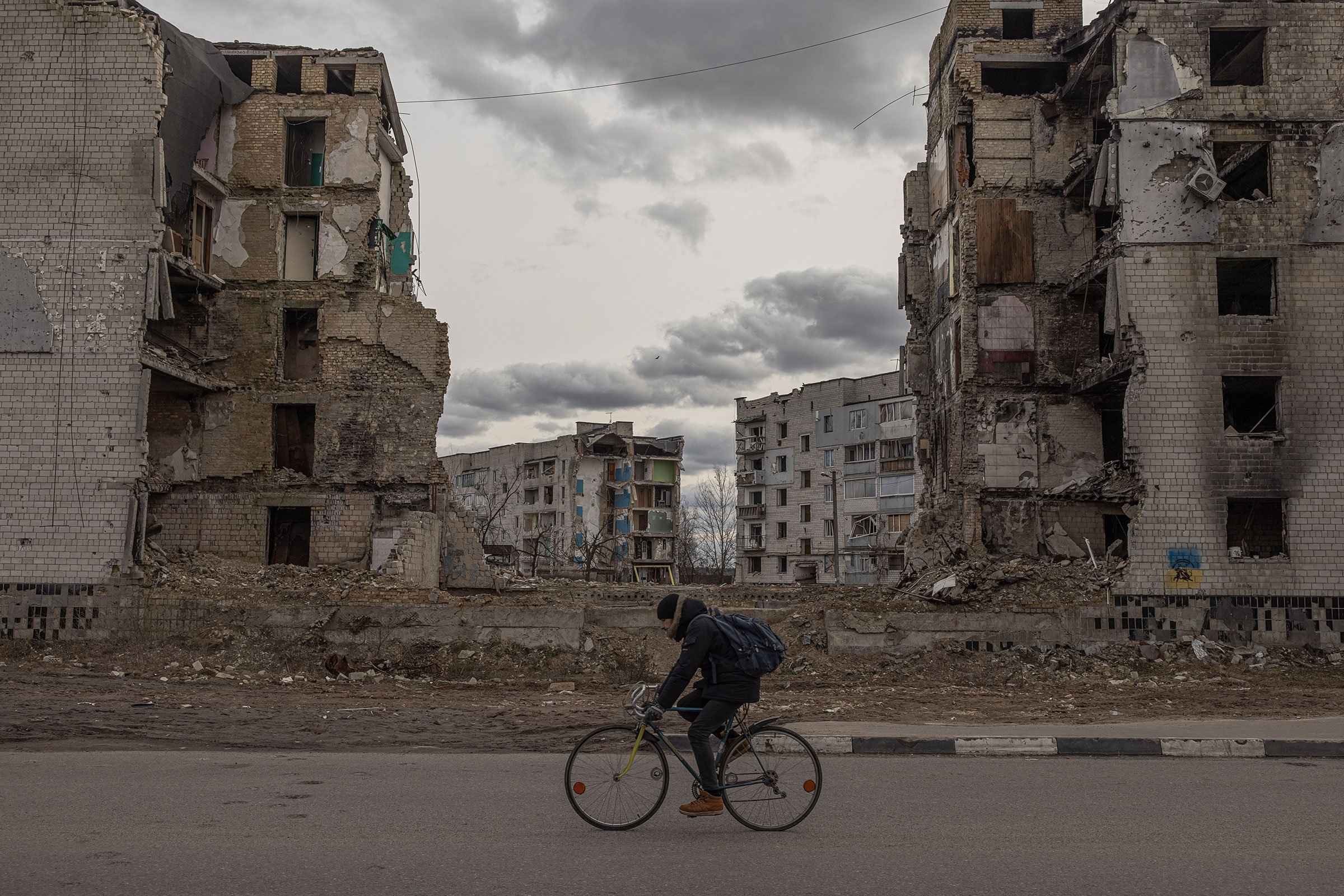 A man rides a bicycle past residential buildings that were destroyed during the Russian attack, on Feb. 20, 2023 in Borodyanka, Kyiv region, Ukraine. (Roman Pilipey—Getty Images)