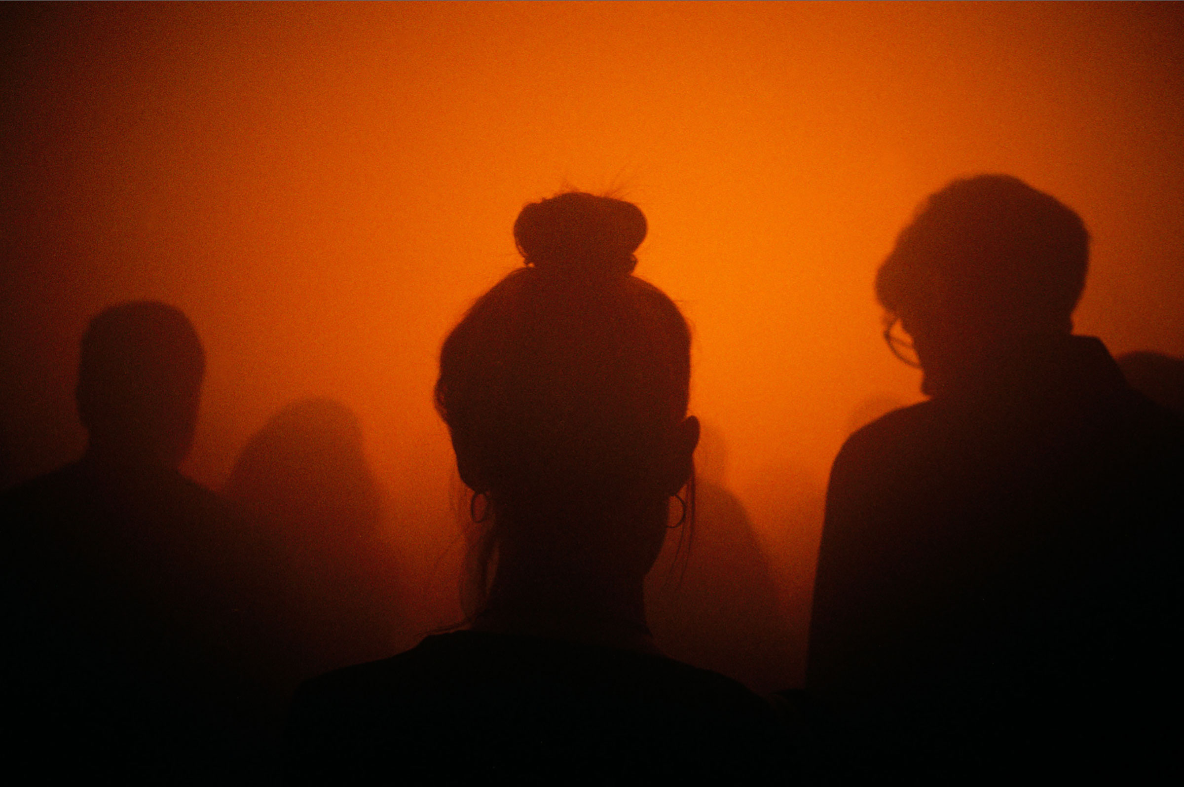 Silhouette of young women in a crowd with smokey orange light