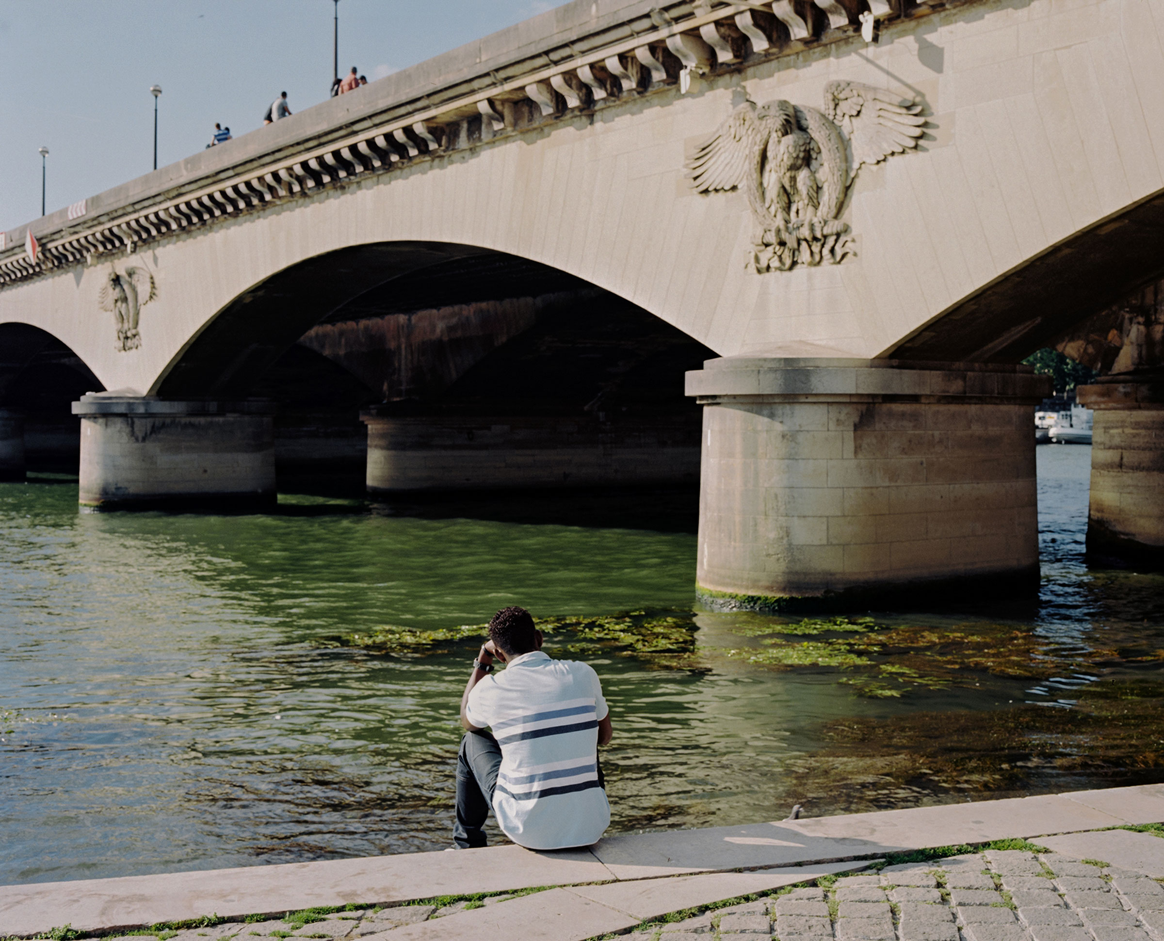 A person sits by the Seine river near the Pont d'Iéna in Paris, France. (Sasha Arutyunova)