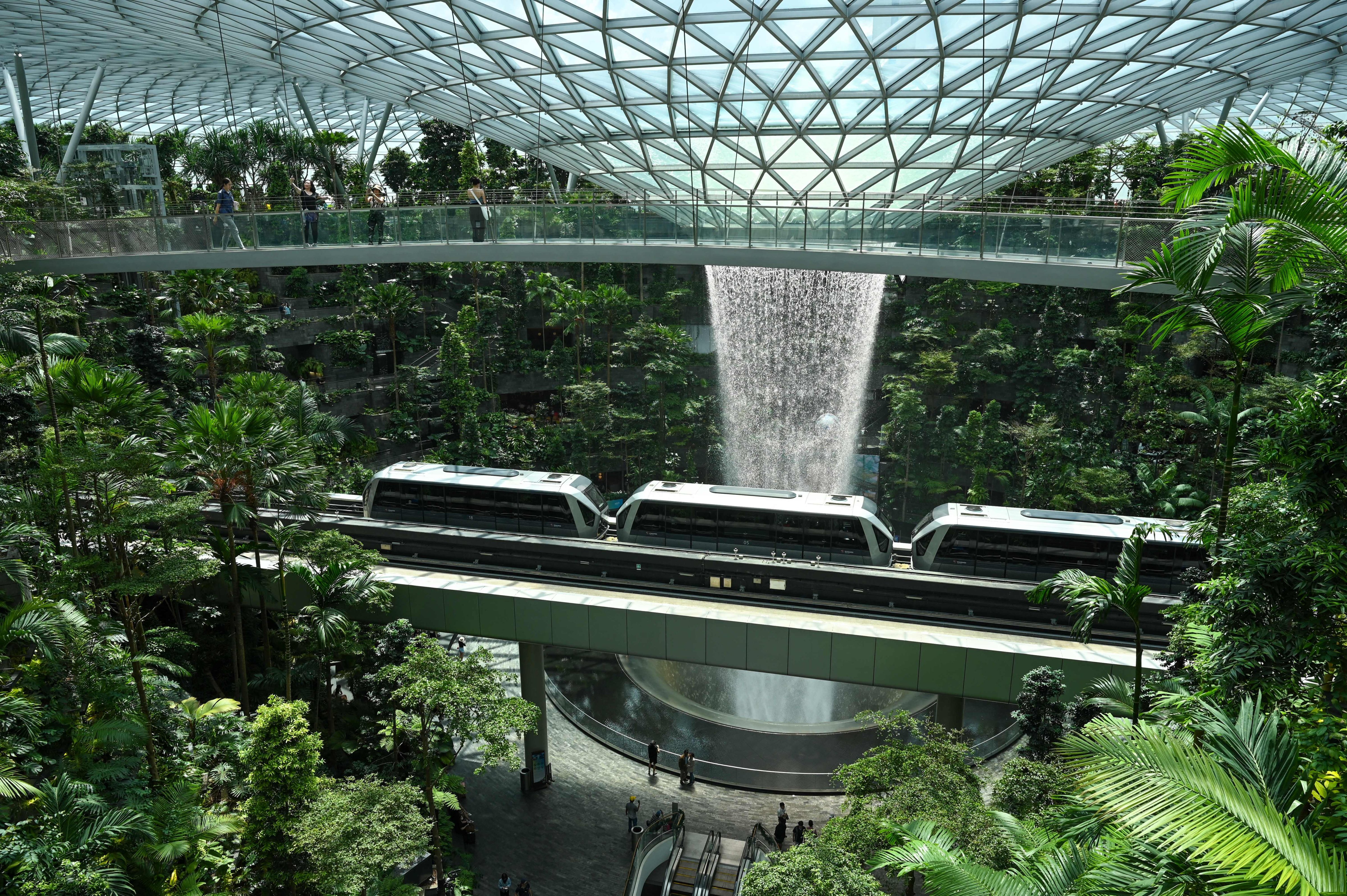 A train passes below an observation bridge of Rain Vortex, the world's tallest indoor waterfall, at Jewel, a nature-themed entertainment and retail complex at Changi Airport in Singapore, on Dec. 7, 2022. (Roslan Rahman—AFP/Getty Images)