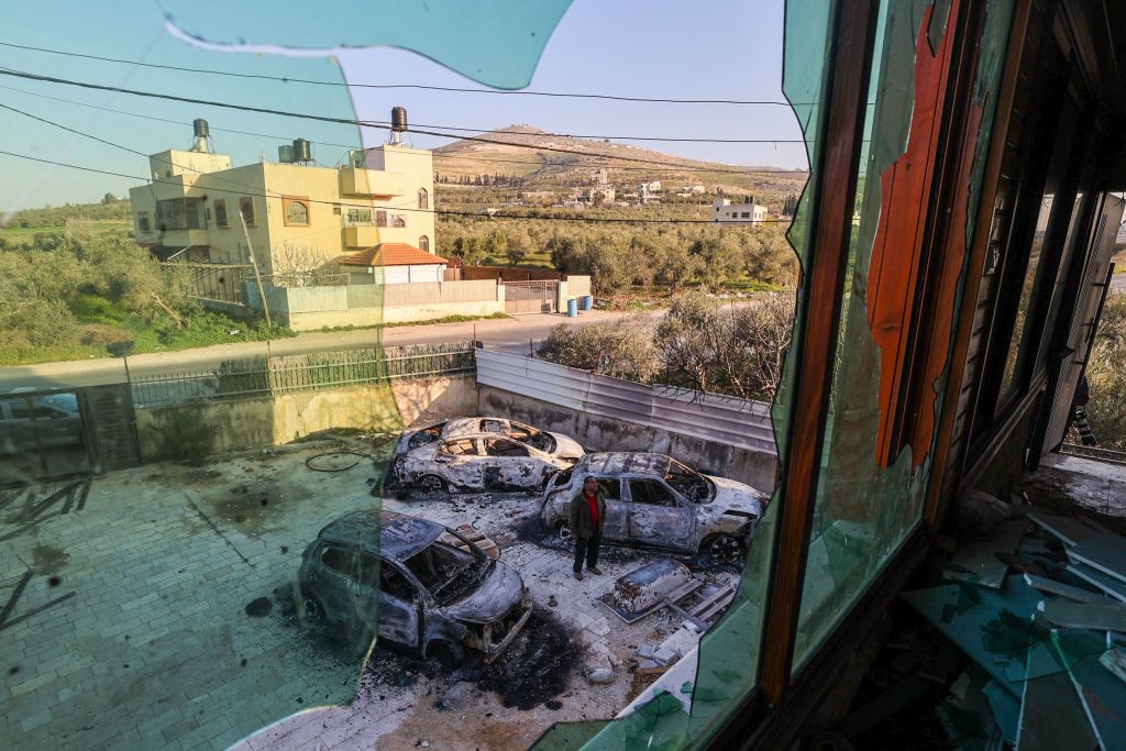 A Palestinian man stands amid torched cars at a scrapyard in a house in Huwara, in the occupied West Bank, on Feb. 27, 2023. (Jaafar Ashtiyeh / AFP via Getty Images)