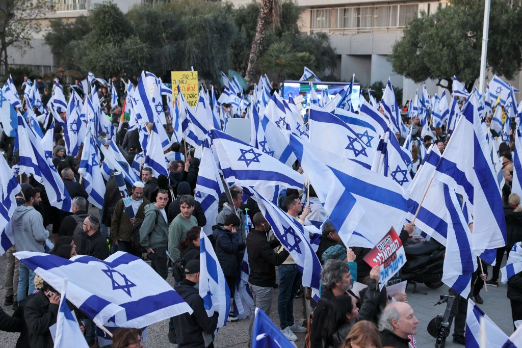 Supporters of Israel's Prime Minister Benjamin Netanyahu (not pictured) lift flags as they demonstrate in support of his government's controversial juducial overhaul bill in Tel Aviv, on March 30, 2023. (JACK GUEZ-AFP)