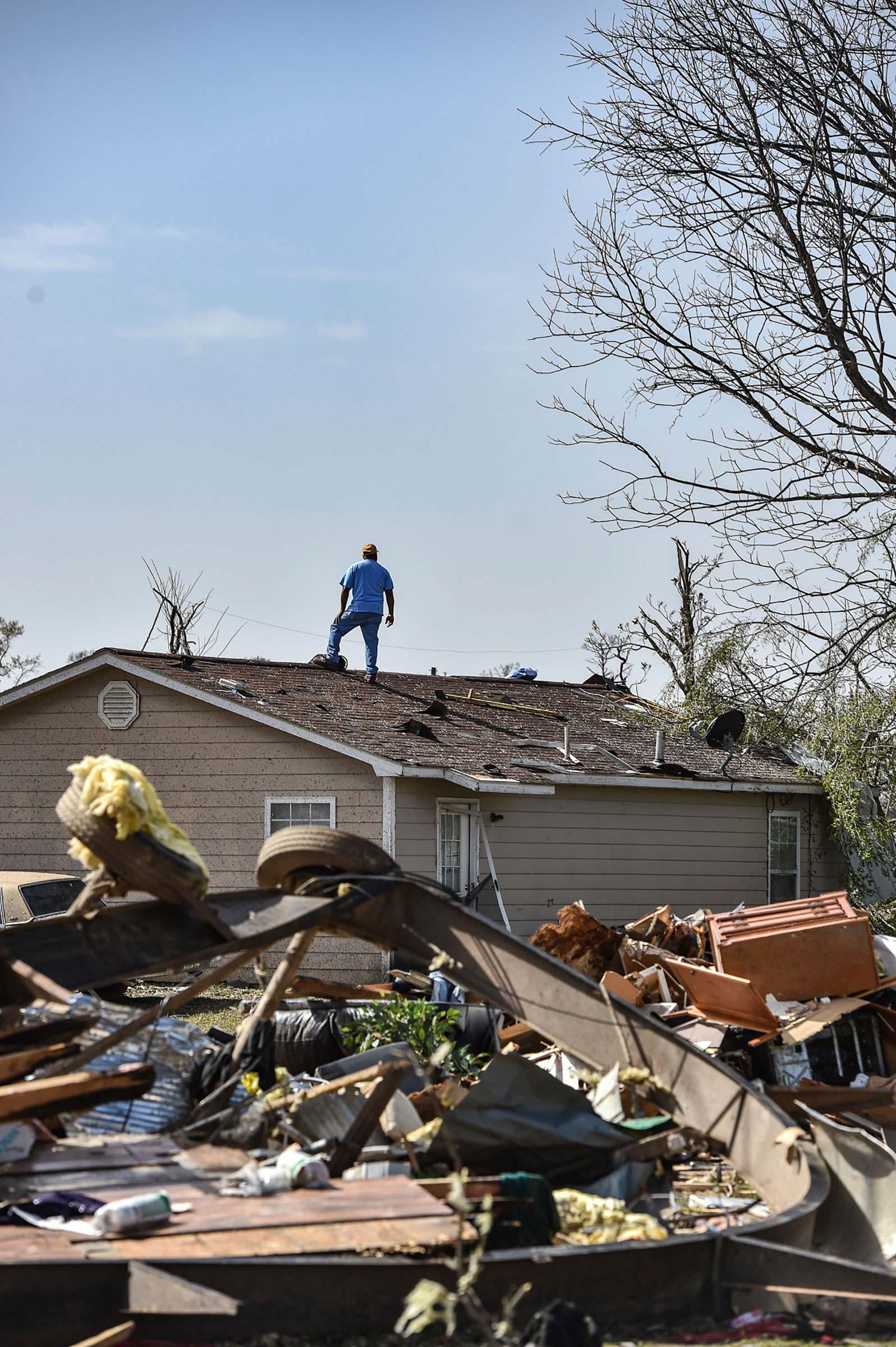 A resident of Silver City, Miss., stands on top of his house on March 25, 2023, to survey the surrounding damage following a deadly tornado that ripped through the state Friday night. (Hannah Mattix—The Clarion-Ledger/AP)