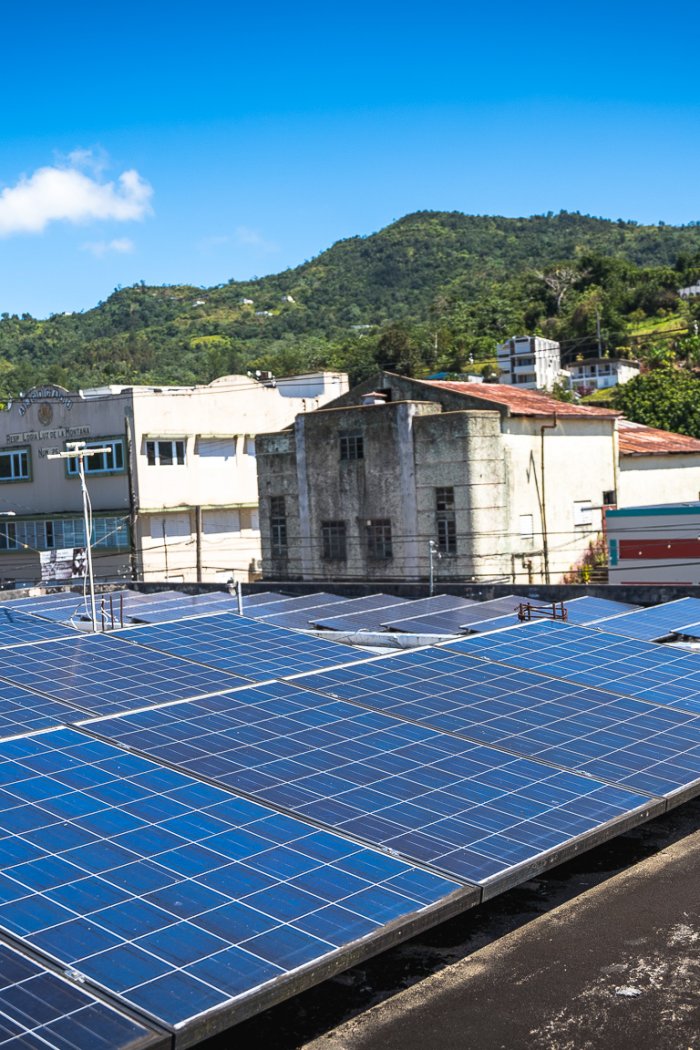 Solar panels on a rooftop in Adjuntas, Puerto Rico, contribute to a new community-owned microgrid project.