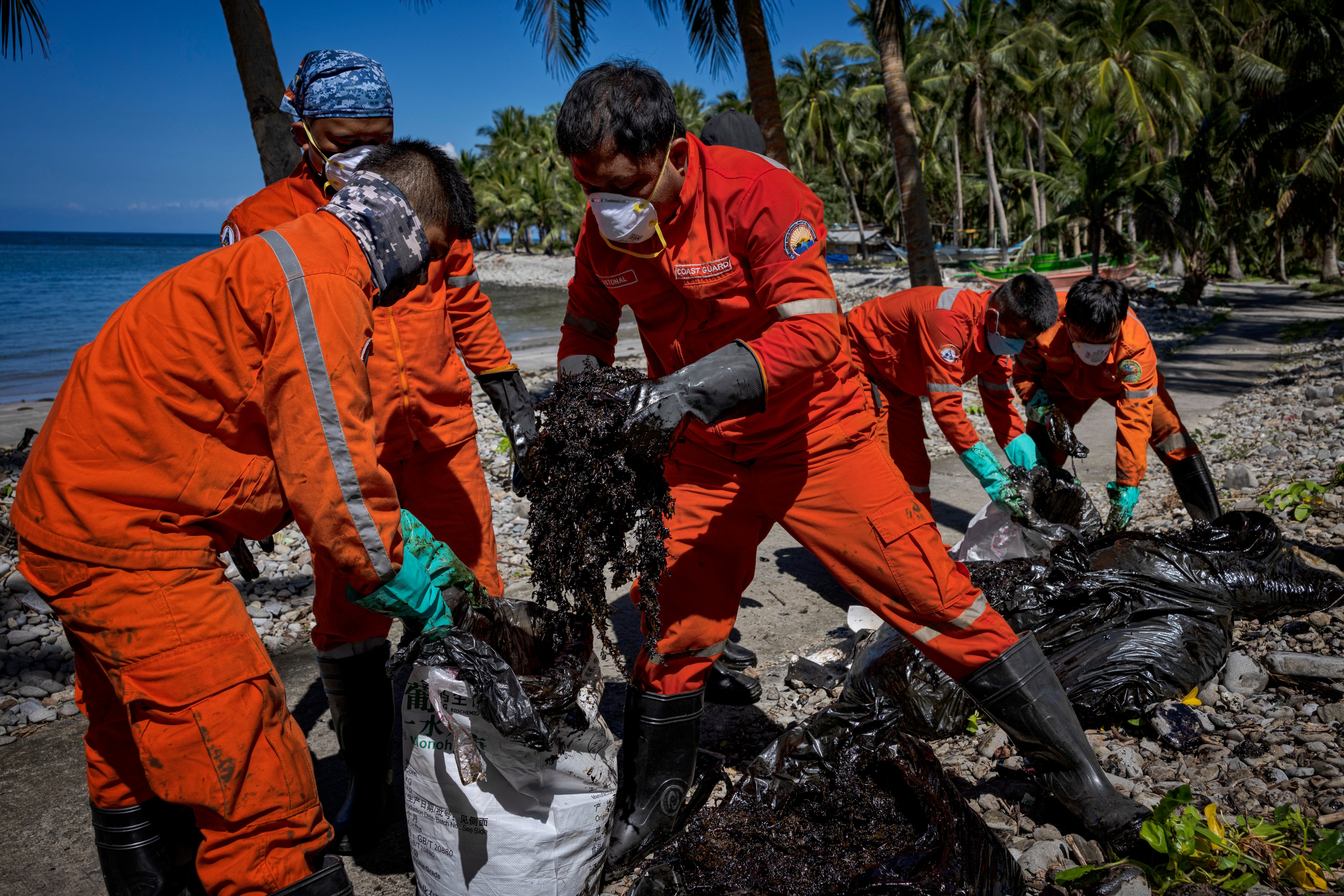 Philippine coast guard personnel clean up oil slick that washed ashore in Pola, Oriental Mindoro, March 08, 2023. (Ezra Acayan/Getty Images)