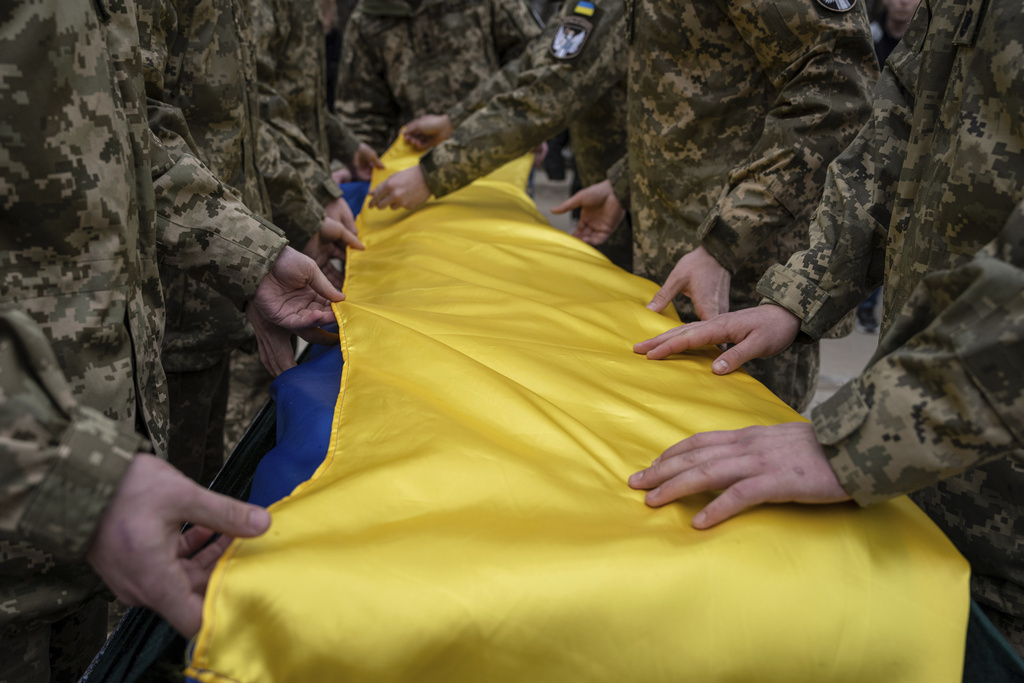 Ukrainian servicemen fold the national flag over the coffin of their comrade Andrii Neshodovskiy during the funeral ceremony in Kyiv, Ukraine, on March 25, 2023. (Evgeniy Maloletka—AP)