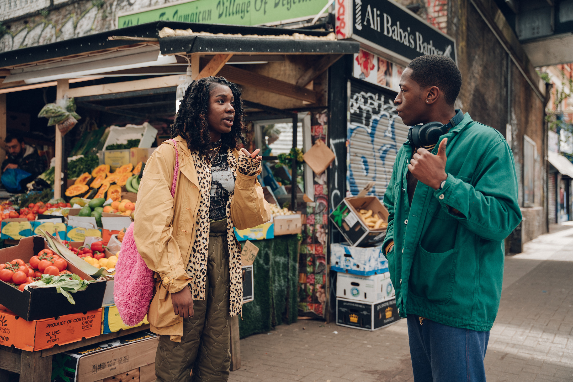 Yas (Vivian Oparah) and Dom (David Jonsson) stroll through the lively streets of Peckham. (Chris Harris—Century Studios)