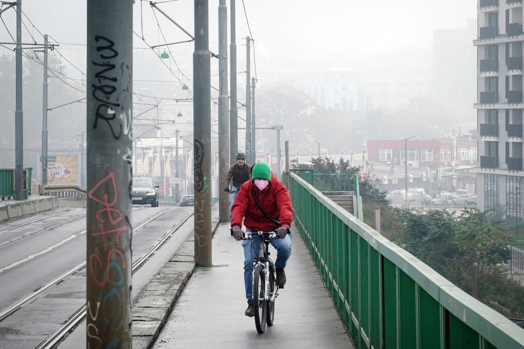 A cyclist wears a protective face mask while riding during heavy smog in Belgrade, Serbia, on Nov. 1, 2022. Smog spewing from ancient coal-fired power plants, outdated automobiles and heating systems running on burning tires and wood is choking the Balkans both literally and economically. (Oliver Bunic/Bloomberg—Getty Images)