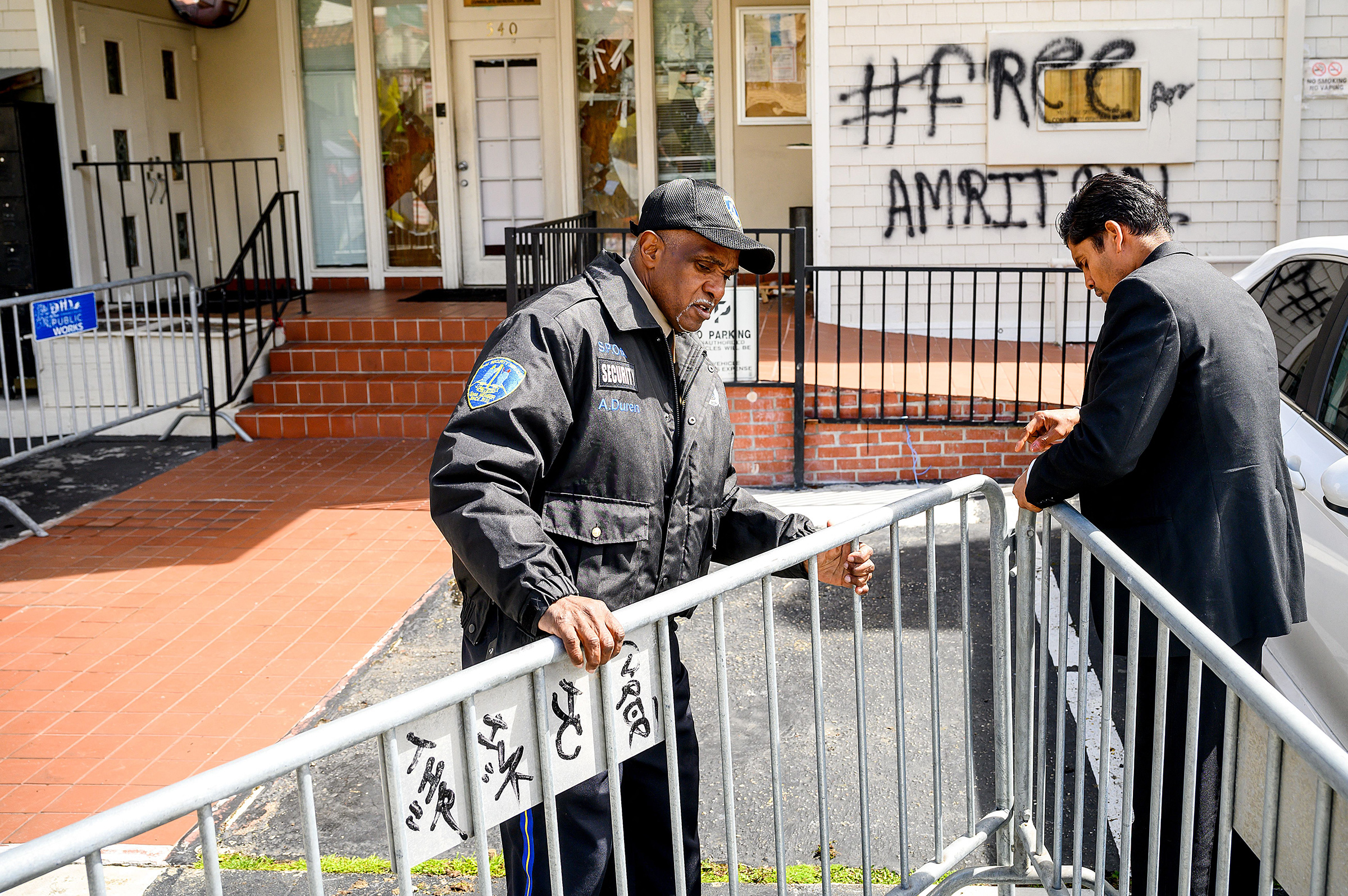 A security guard adjusts barricades at the Indian Consulate as broken windows and a graffitti reading "FreeAmritpal" are seen behind, in San Francisco, Calif. on March 20. Indian authorities extended a mobile internet blackout across a state of about 30 million people on Monday as police hunted a radical Sikh preacher. The blackout extension came after supporters of Amritpal Singh were filmed vandalising India's consulate in San Francisco. (Noah Berger—AFP/Getty Images)