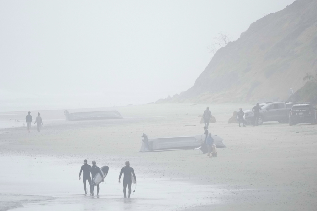 Two boats, one overturned, sit on Blacks Beach  in San Diego, Calif. on March 12, 2023. (Gregory Bull—AP)