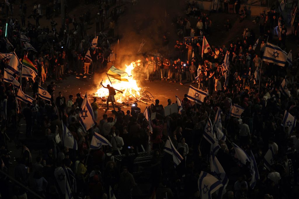 Protesters block a road and hold national flags as they gather around a bonfire during a rally against the Israeli government's judicial reform in Tel Aviv on March 27, 2023. (Ahmad Gharabli—AFP/Getty Images)