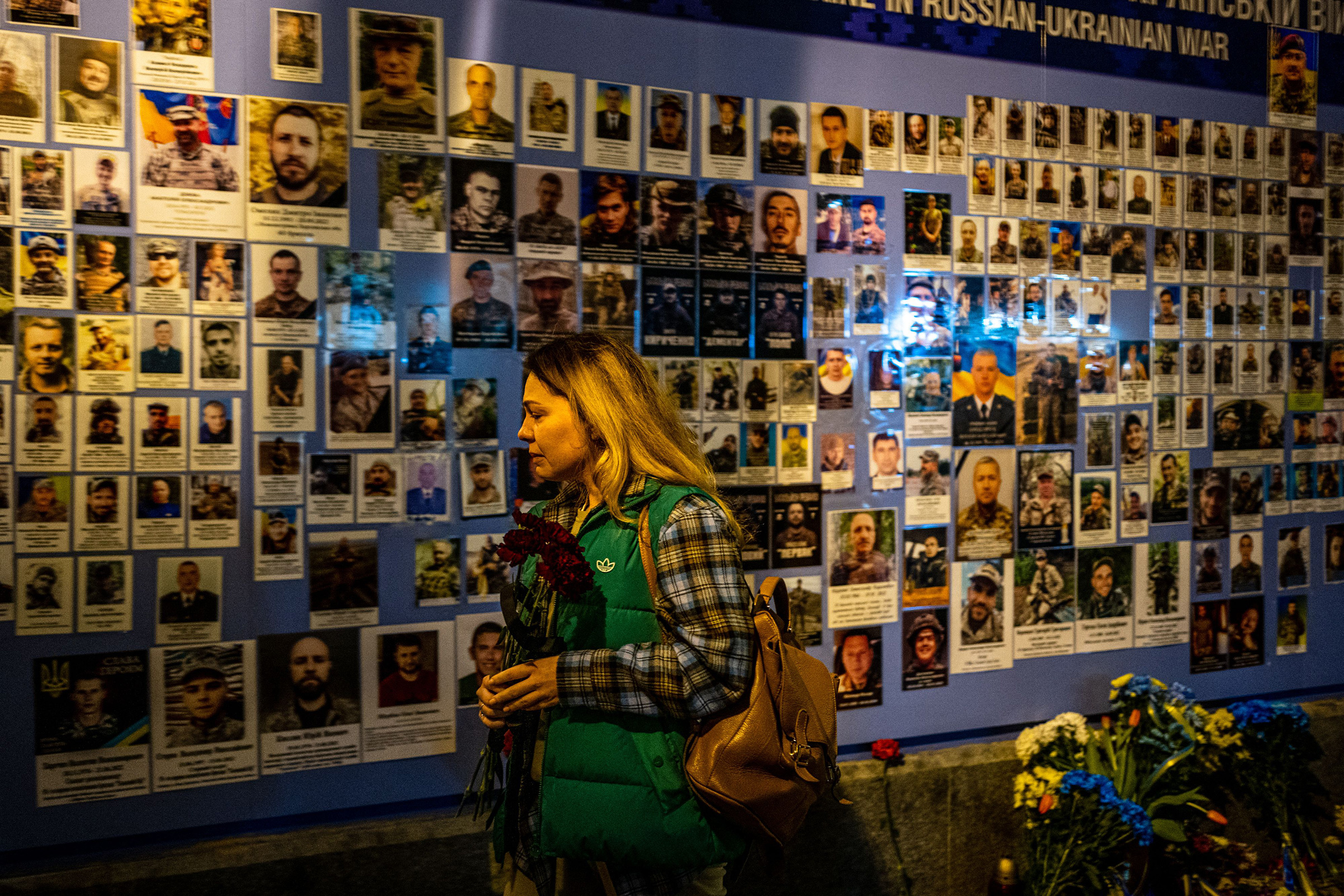 A woman reacts in front of pictures displayed at a Memory Wall of Fallen Defenders of Ukraine in Kyiv on Feb. 24, on the first anniversary of the war. (Dimitar Dilkoff—AFP/Getty Images)