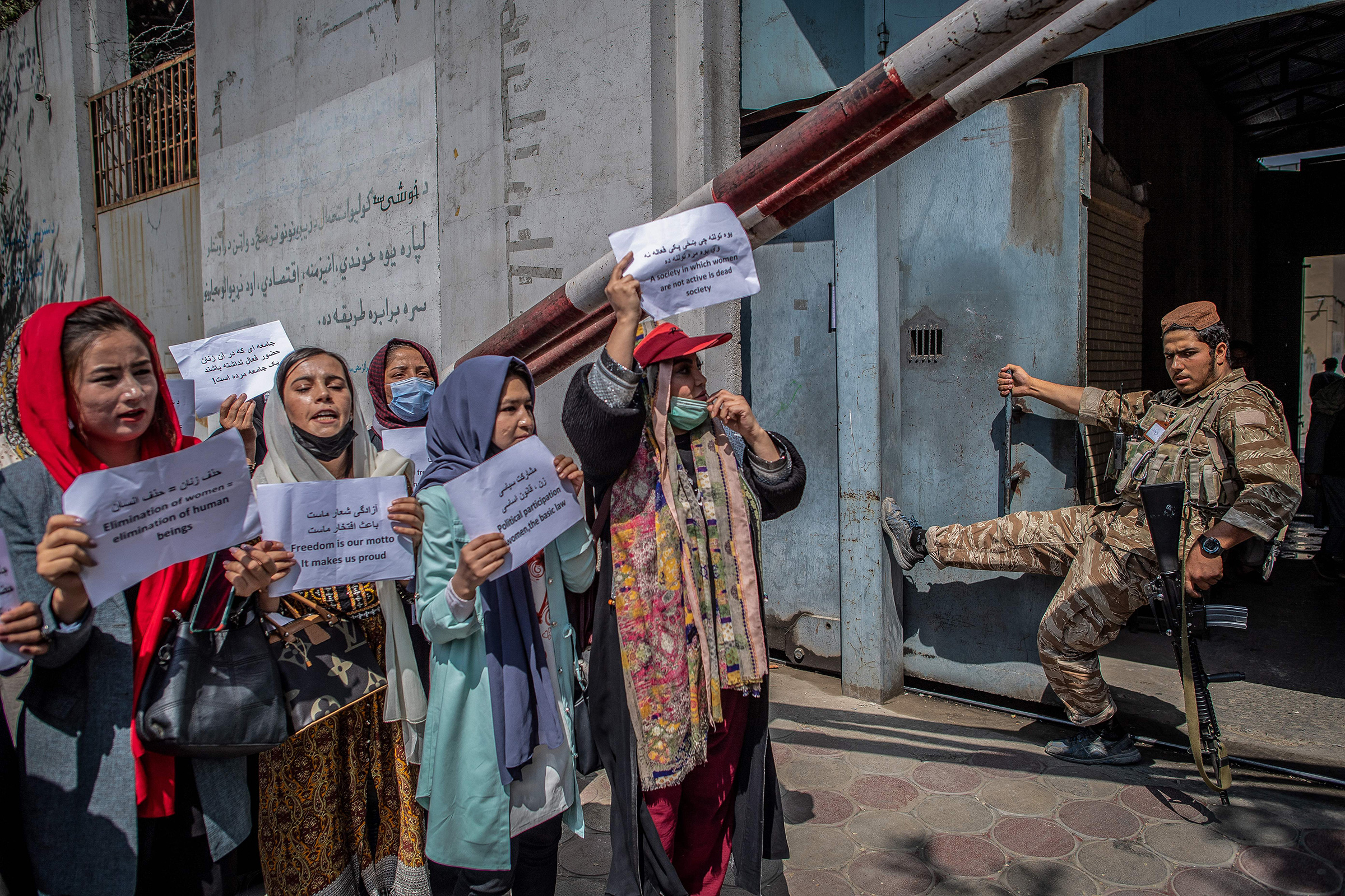 A Taliban fighter watches as Afghan women hold placards during a demonstration demanding better rights for women in front of the former Ministry of Women Affairs in Kabul on Sept. 19, 2021. (Bulent Kilic—AFP/Getty Images)