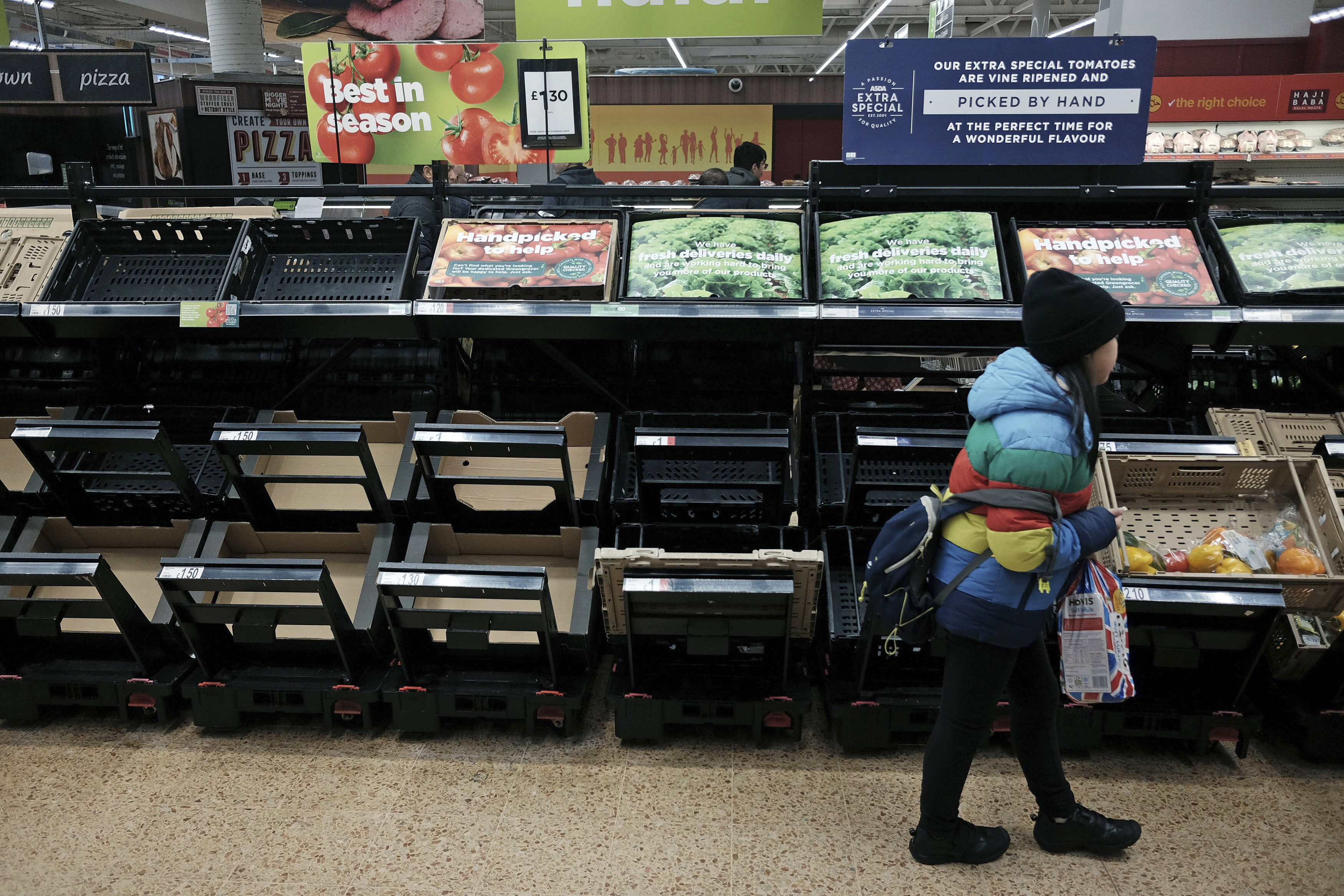 A girl walks by empty fruit and vegetable shelves at an Asda in east London, Saturday, Feb. 25, 2023. British people have had to ration tomatoes and cucumbers for the past two weeks amid a shortage of fresh vegetables. (Yui Mok–PA/AP)