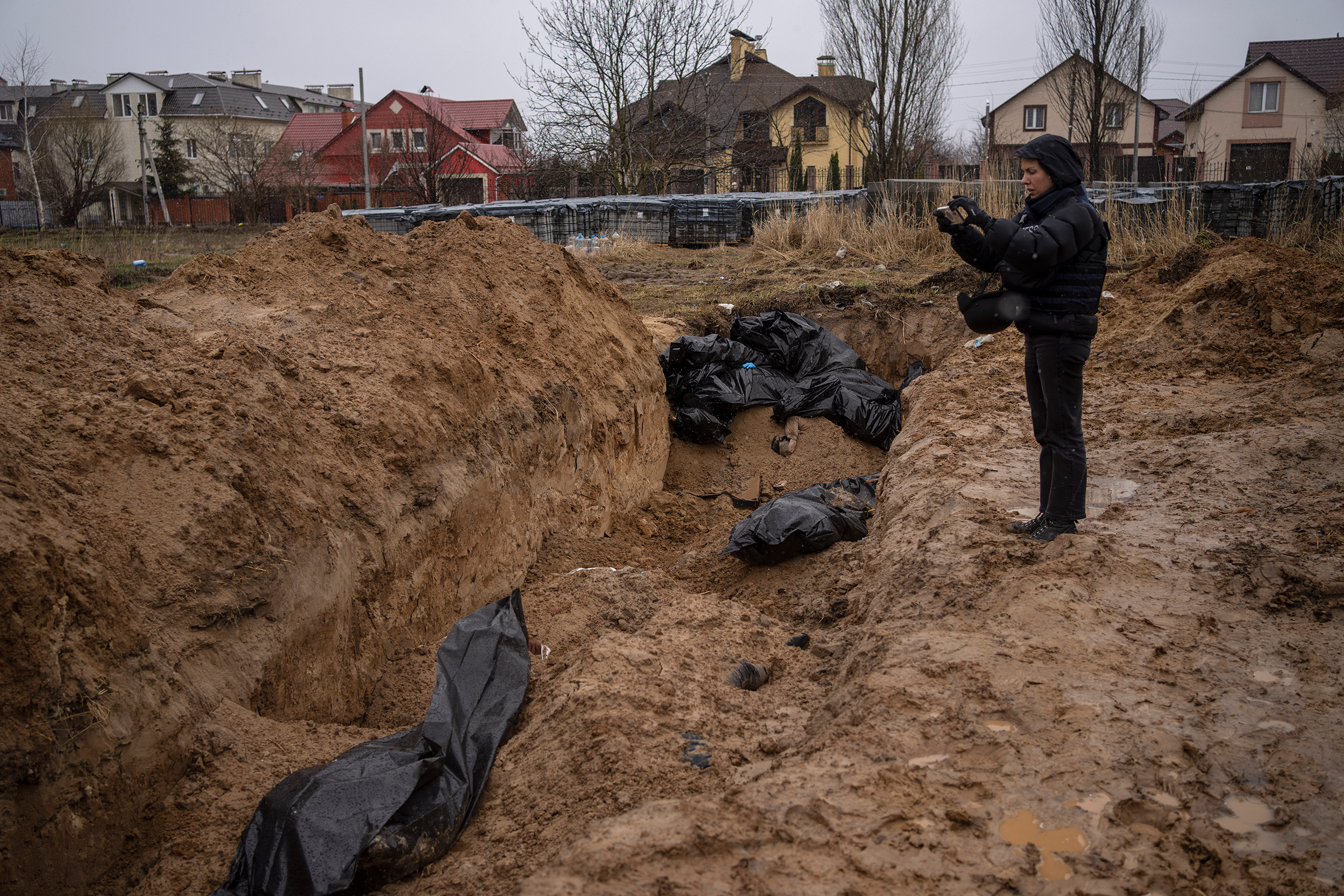 A journalist takes video of a mass grave in Bucha, on the outskirts of Kyiv, Ukraine, Sunday, April 3, 2022. Ukrainian leaders have encouraged journalists to document what is happening in the country. (Rodrigo Abd—AP)