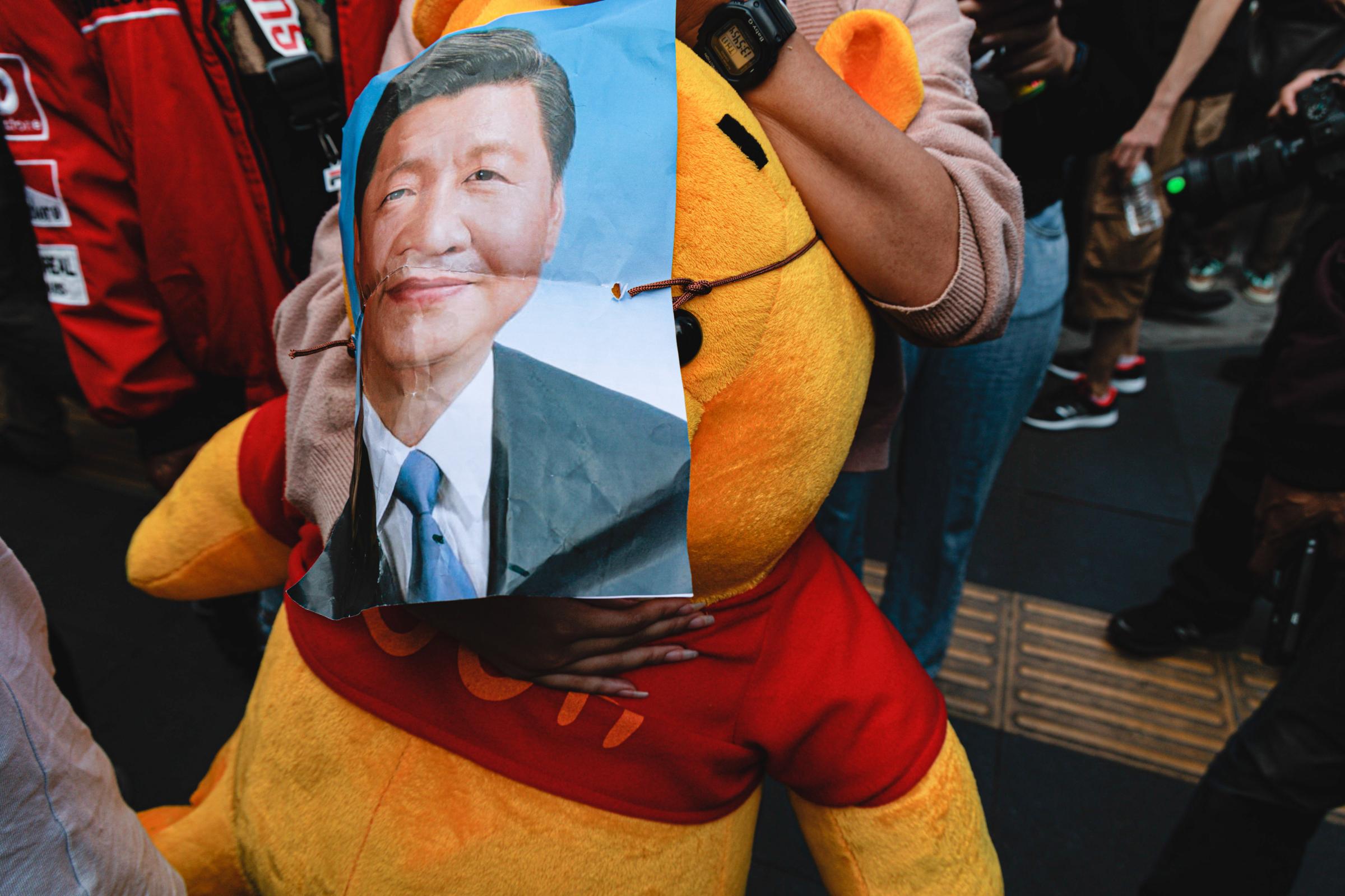 A protester holds a pooh bear with a poster of Xi Jinping