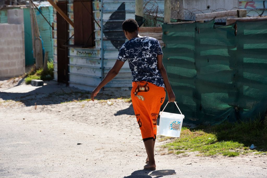 Woman carries water in Cape Town informal neighborhood