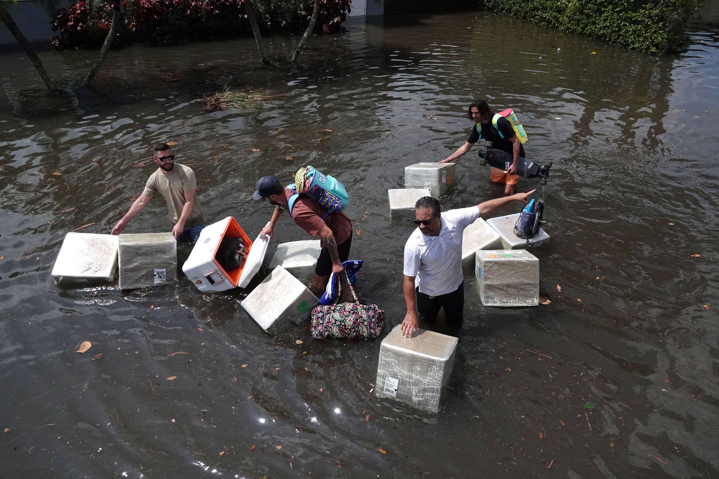 People try to save valuables as they wade through flood waters in the Edgewood neighborhood of Fort Lauderdale, Fla., on April 13, 2023. (Joe Cavaretta—South Florida Sun-Sentinel/AP)