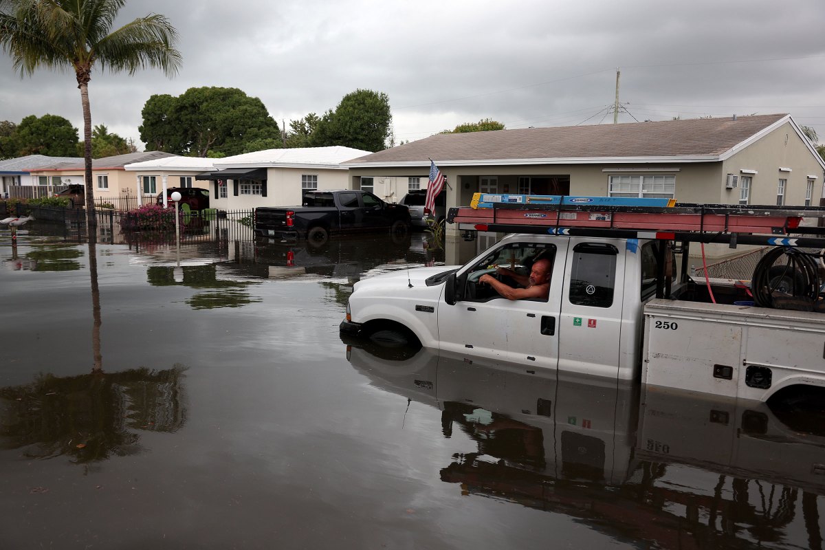A person sits in a stalled truck along a flooded street in Fort Lauderdale