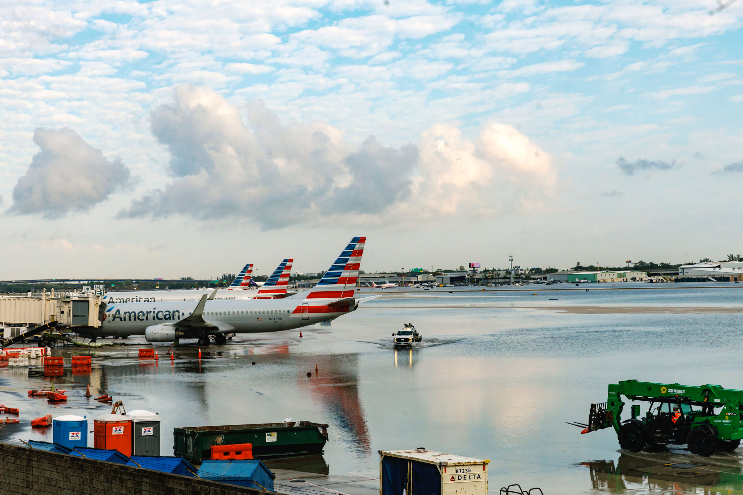 American Airlines airplanes sit at the terminal as a truck drives through the flooded tarmac at the Fort Lauderdale-Hollywood International Airport on April 13, 2023. (David Santiago—Miami Herald/AP)
