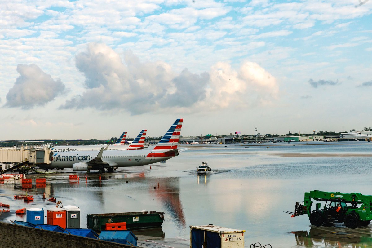 American Airlines airplanes sit at the terminal as a truck drives through the flooded tarmac at the Fort Lauderdale-Hollywood International Airport