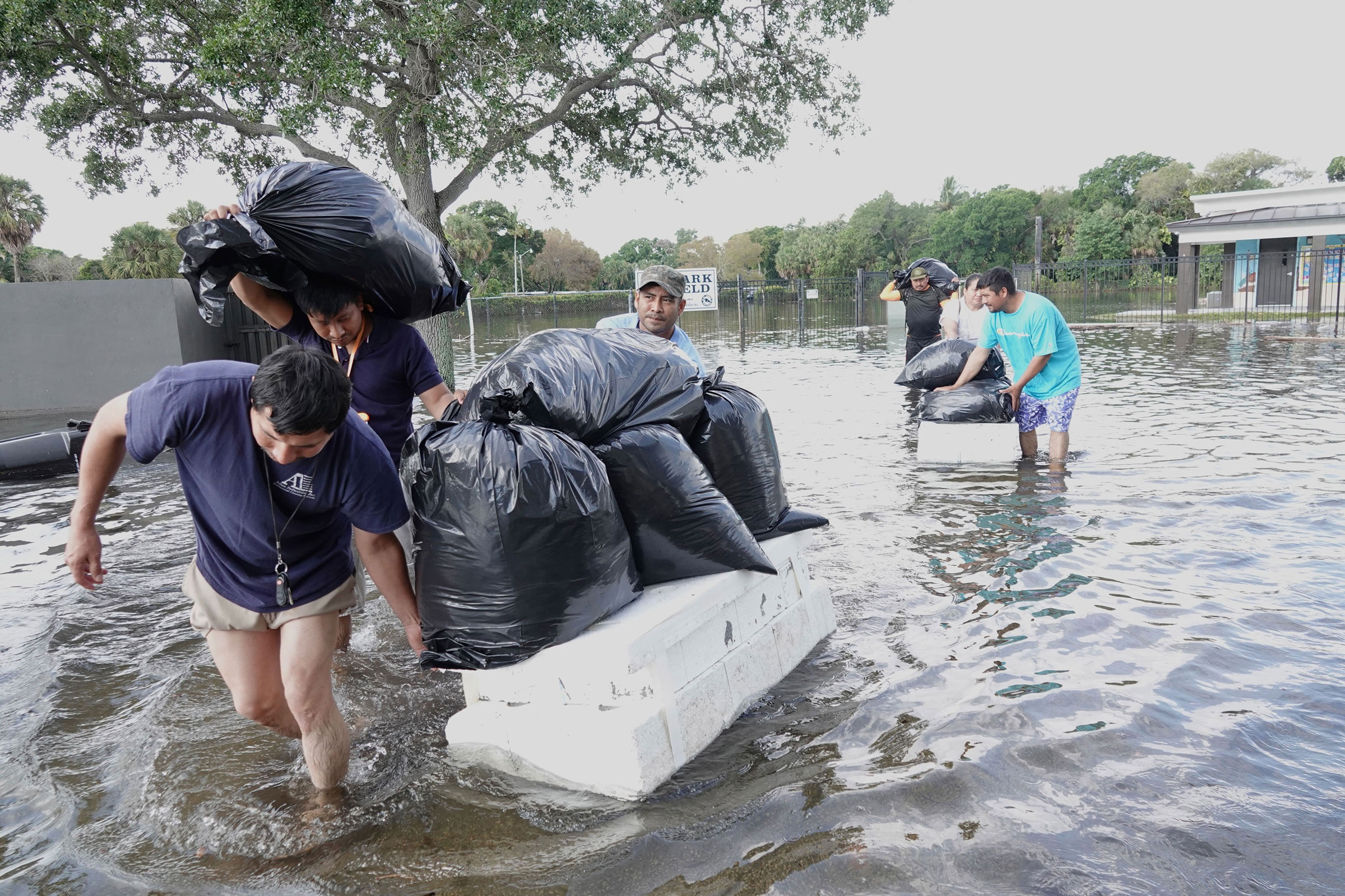 People try to save valuables as they wade through flood waters in the Edgewood neighborhood of Fort Lauderdale, Fla., on April 13, 2023.