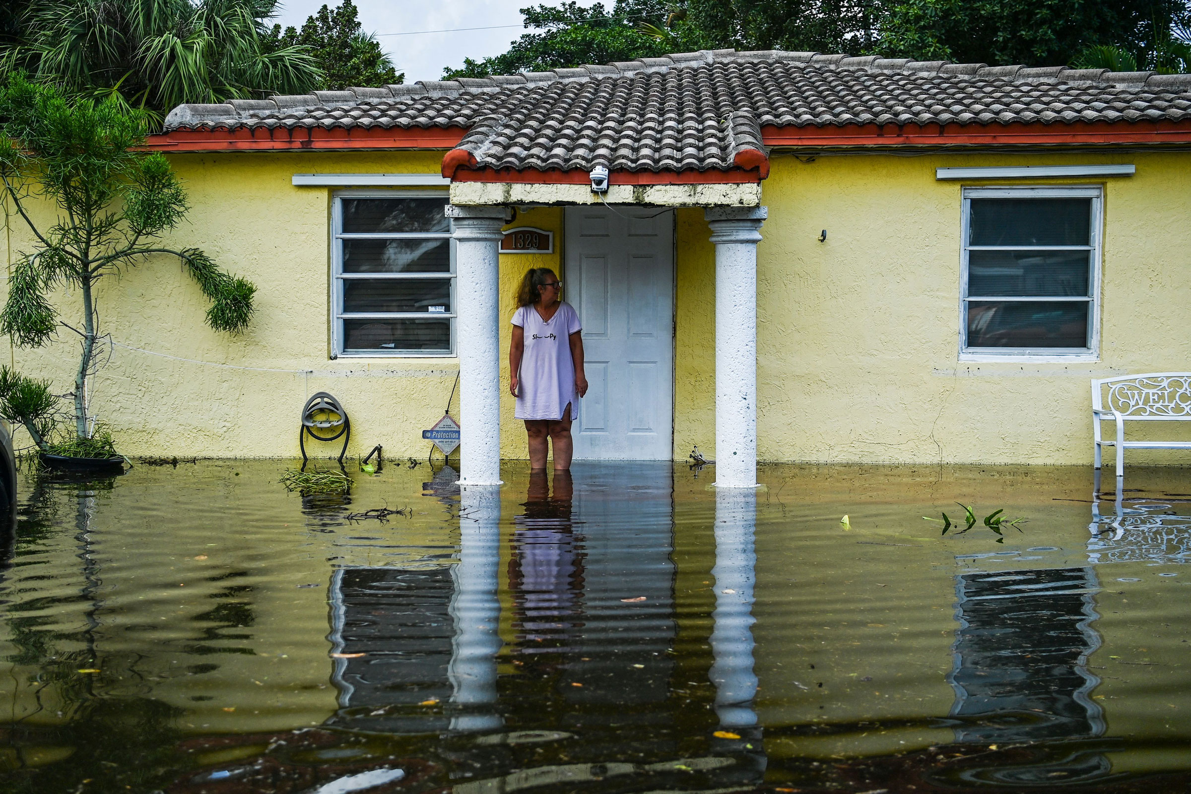 A woman looks on as she stands outside of a flooded home after heavy rain in Fort Lauderdale, Fla., on April 13, 2023.