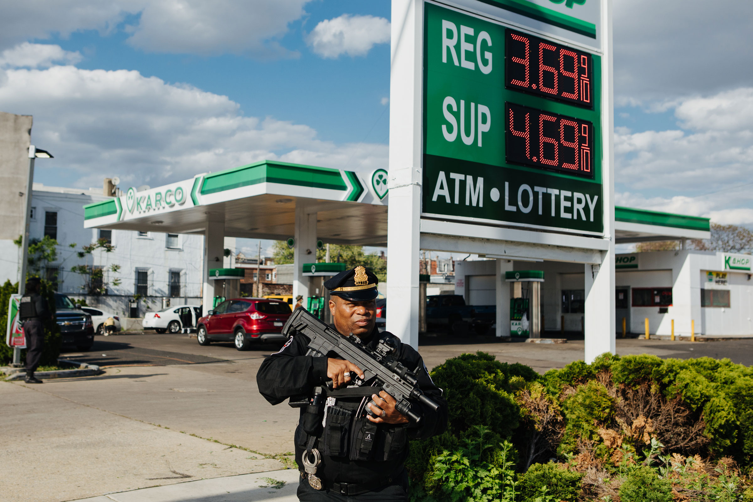 Andre Boyer, an agent for the Strategic Intervention Tactical Enforcement (S.I.T.E.), is seen patrolling the sidewalk outside of a Karco gas station in North Philadelphia, Pa., armed with a Bullpup shotgun, on April 24, 2023. (Michelle Gustafson for TIME)
