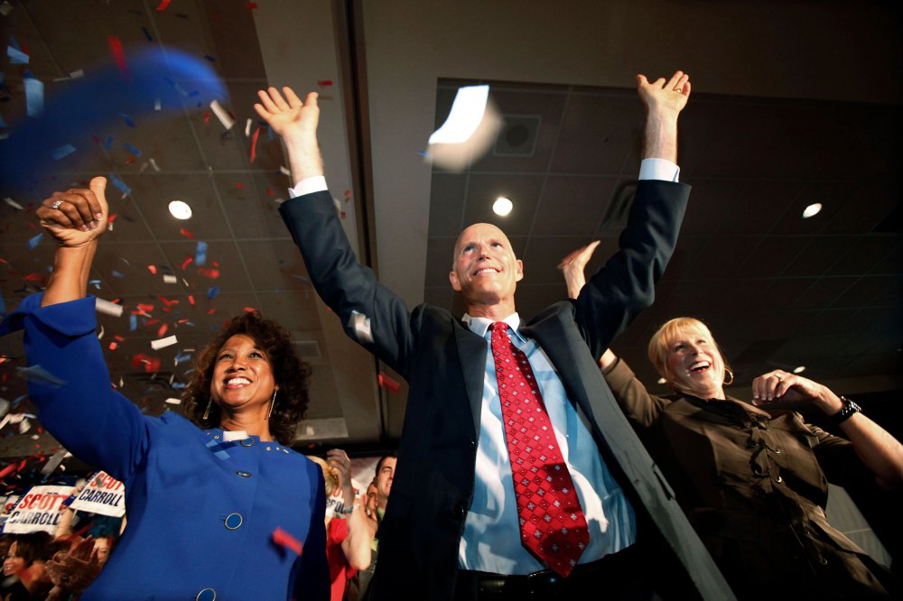 Then Florida Gov.-elect Rick Scott his wife Ann, right, and Lt. Gov.-elect Jennifer Carroll, left, wave to supporters after Scott's victory speech, in Fort Lauderdale, Fla. on Nov. 3, 2010.