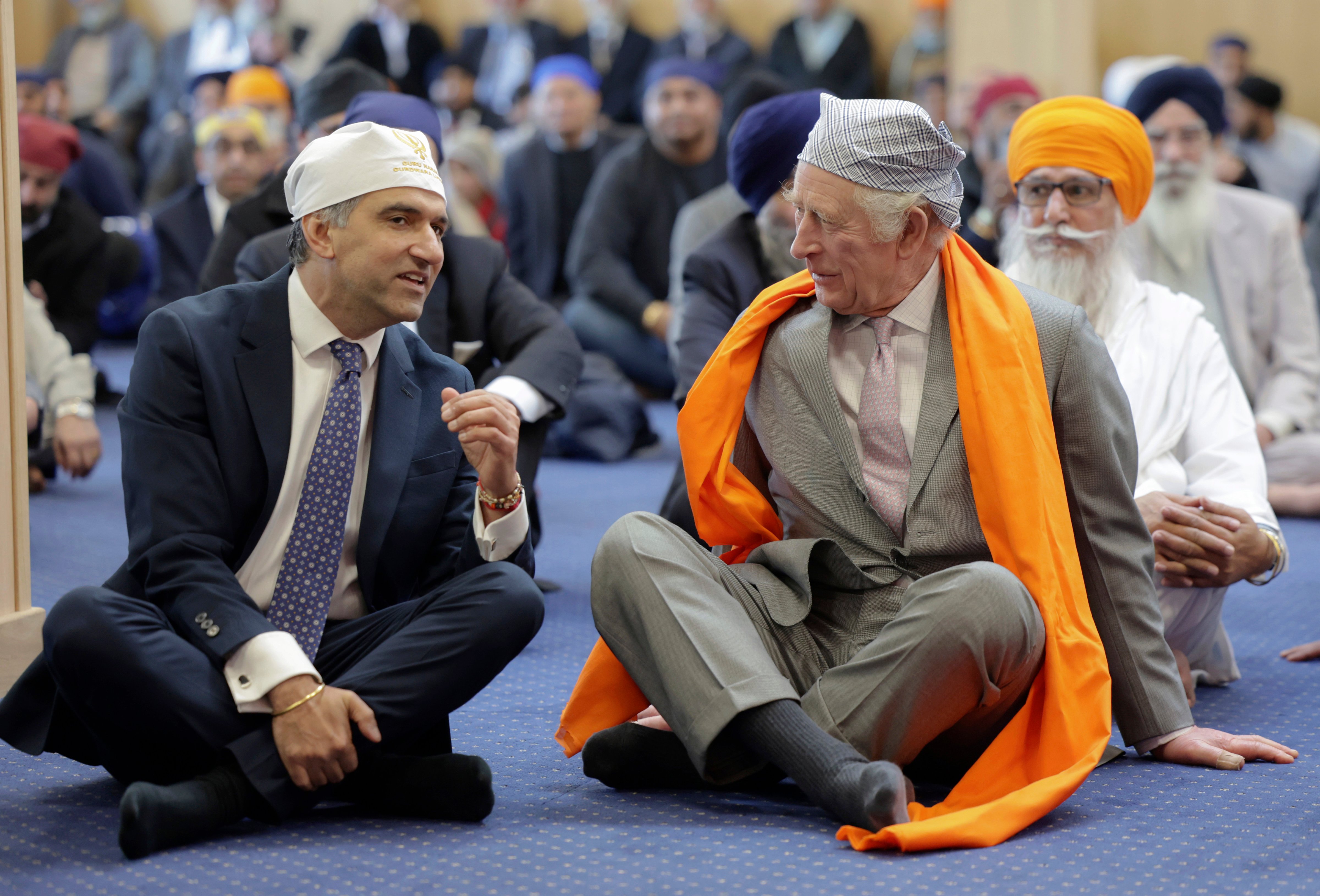 Britain's King Charles III, right, speaks with Professor Gurch Randhawa, a member of the Sikh Congregation, as they sit on the floor in the Prayer Hall during the king's visit to the newly built Guru Nanak Gurdwara, in Luton, England, Tuesday, Dec. 6, 2022. (Chris Jackson—Pool Photo via AP)