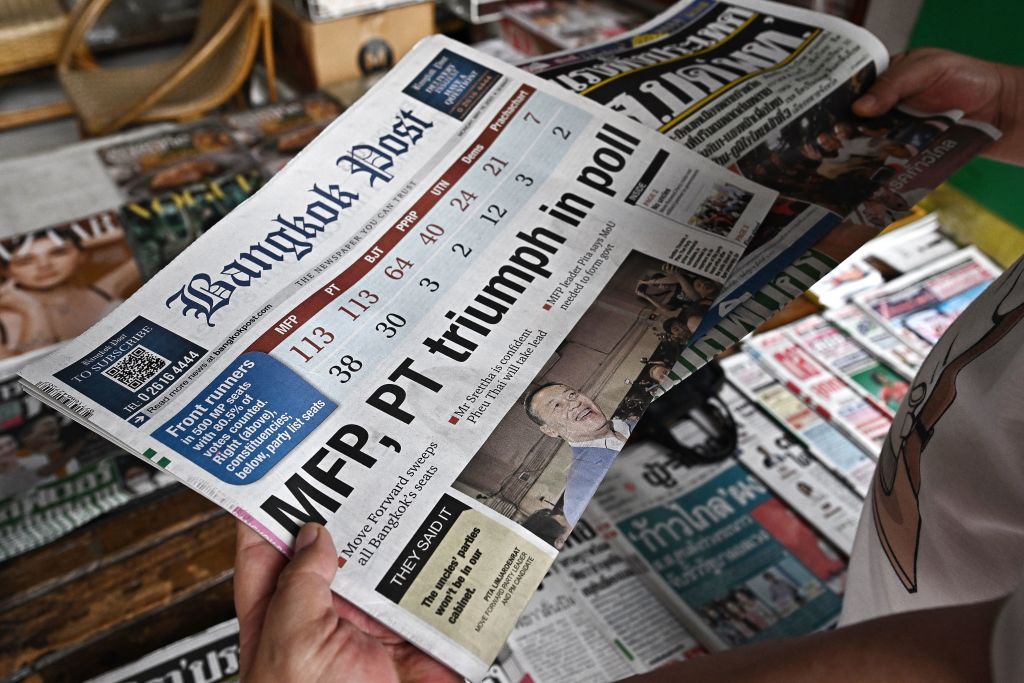 A man reads a Thai newspaper featuring front page coverage of Thailand's general election results, at a newsstand in Bangkok on May 15, 2023. (Lillian Suwanrumpha—AFP/Getty Images)